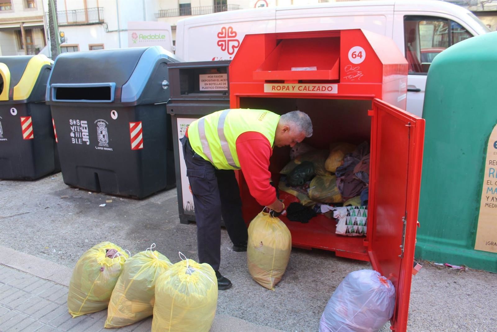 Un trabajador de Recuperaciones Redoble recoge ropa de un contenedor en Jaén.