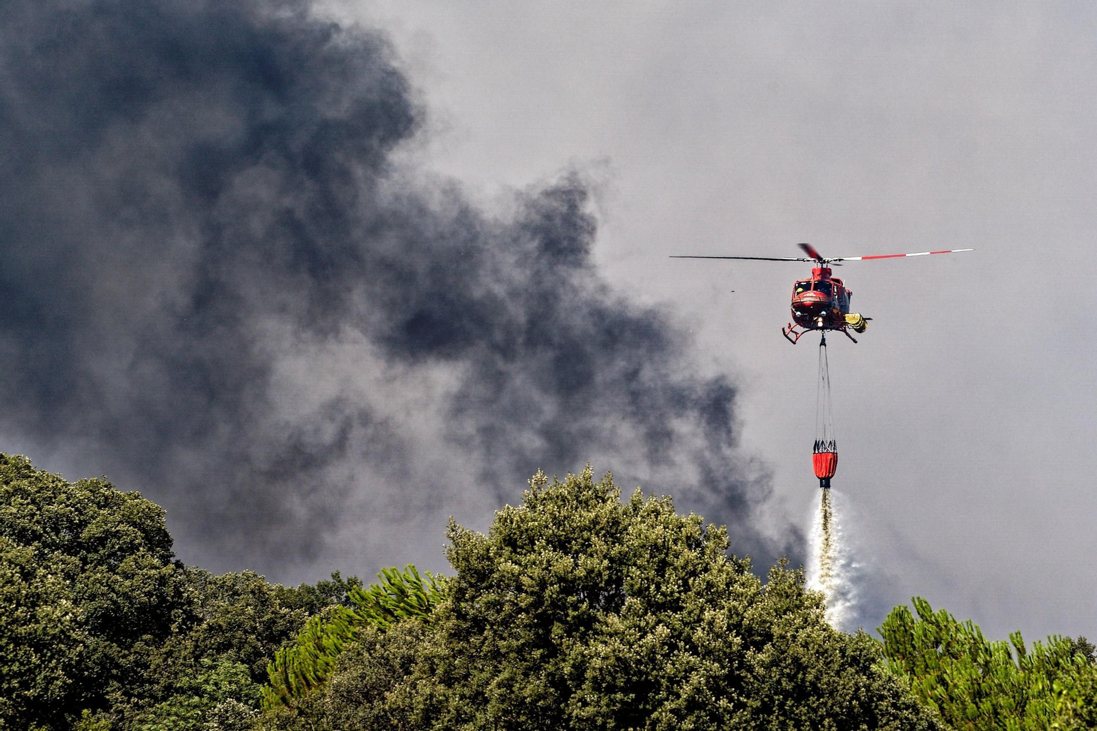 Un helicóptero tira agua sobre un foco del incendio de Navaluenga.