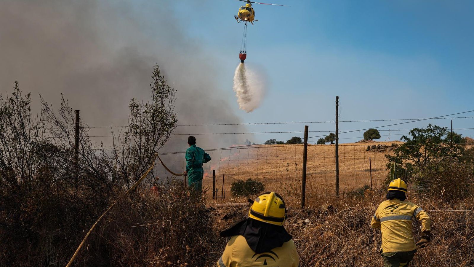 Un helicóptero descarga agua sobre la zona incendiada en Zalamea.