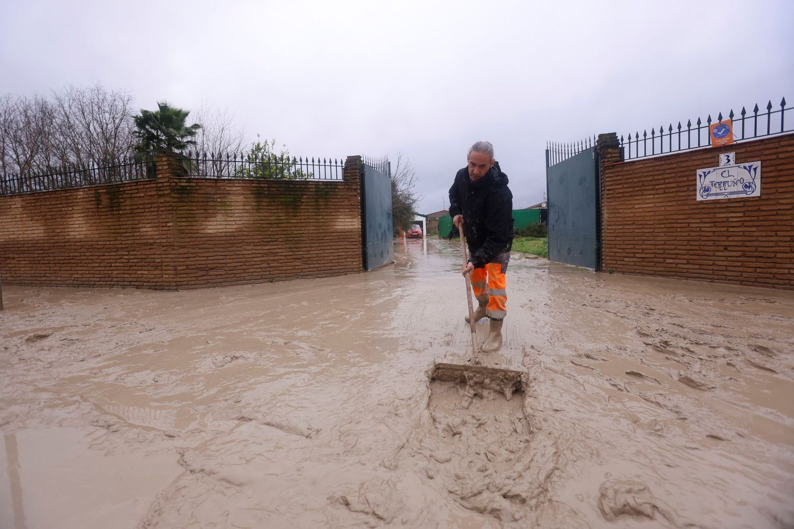 Un vecino limpia su vivienda en la parcelación de Guadalvalle, próxima al aeropuerto de Córdoba.