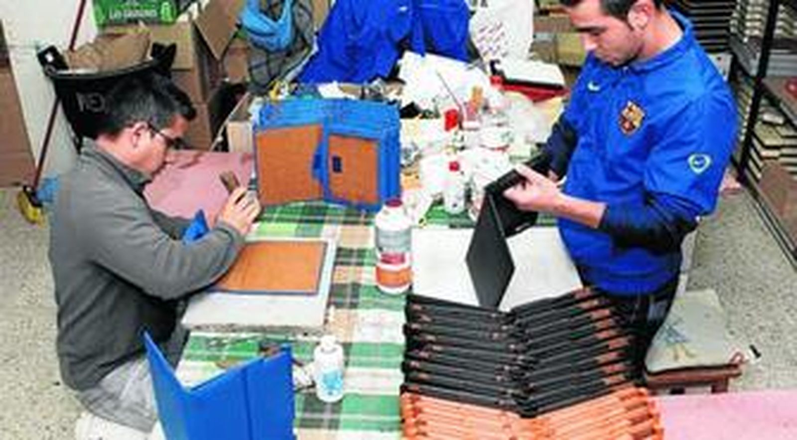 Dos trabajadores rematan las fundas para la nueva versión del Ipad 3, en las instalaciones de Piel Frama.