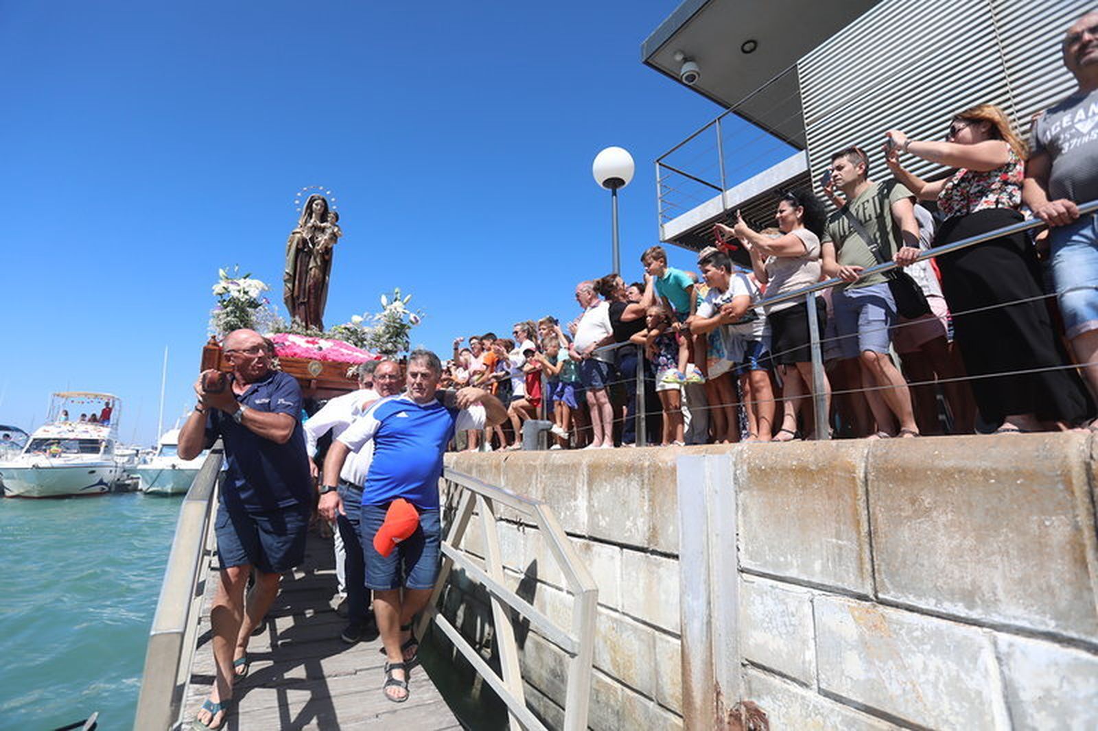 Numerosas personas se dan cita cada año en el muelle del poblado para ver la salida de la Virgen del Carmen en la embarcación.