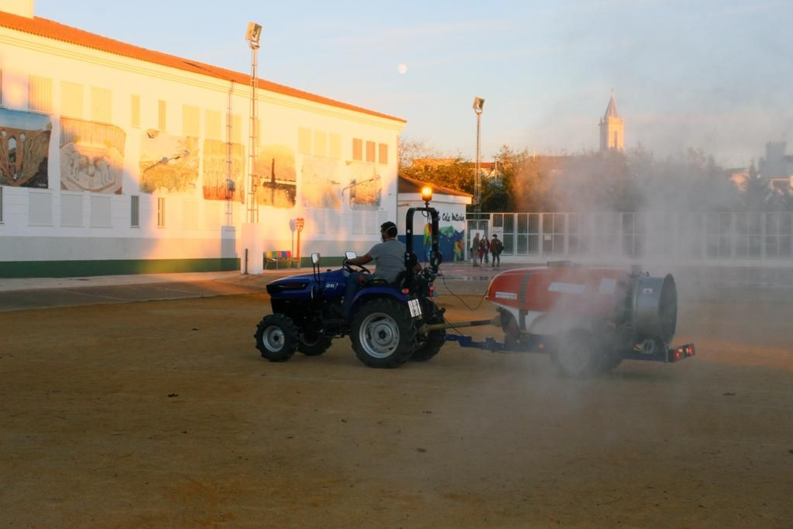 Un tractor realiza labores de desinfección en el patio de un centro educativo de Cartaya.