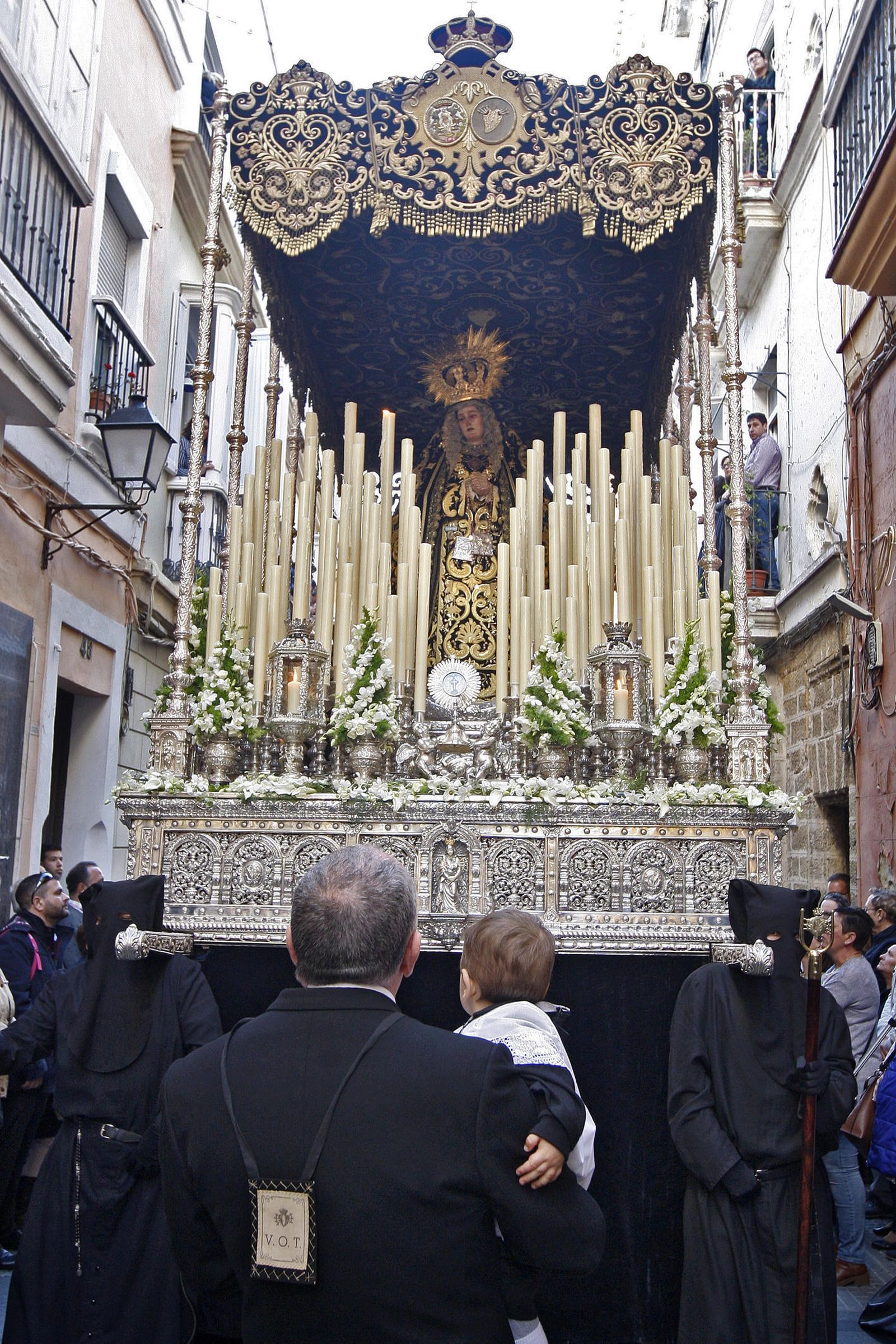 El capataz, José Julio Reyeros, contempla el paso de palio con un niño en brazos.