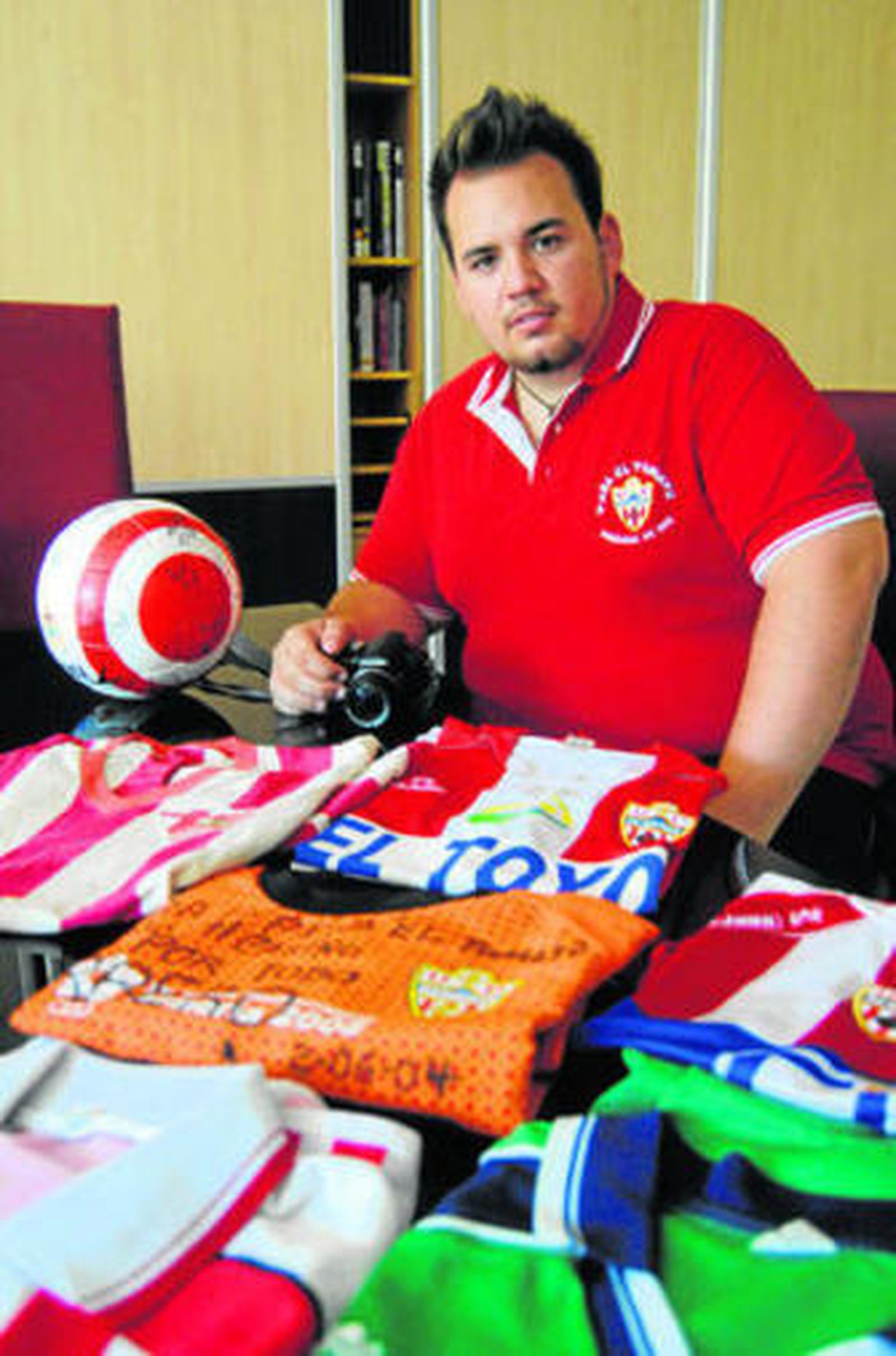 Jorge, con camisetas de todos los años de distintos Almería y su cámara de fotos.