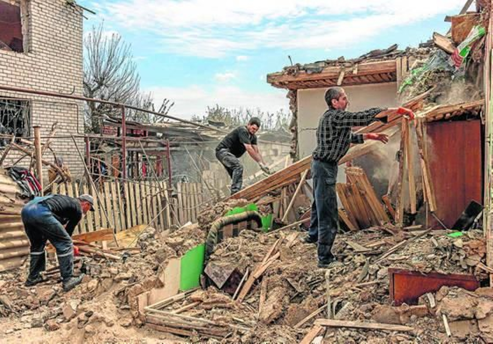 Unos hombres reconstruyen sus viviendas destrozadas por los bombardeos en la localidad ucraniana de Zaporiya.