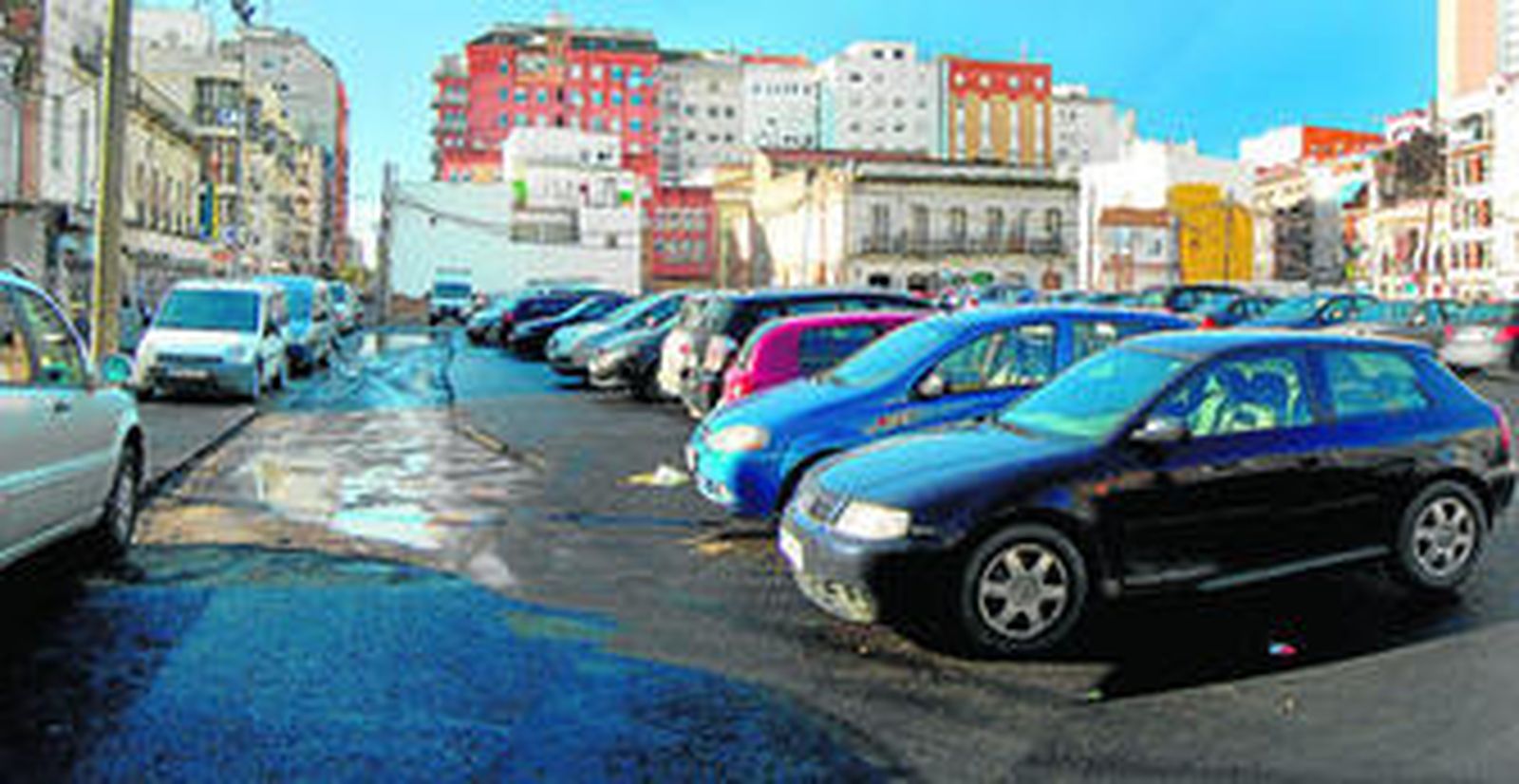 Vehículos estacionados en el solar de la vieja plaza de abastos, donde aún quedan espacios por asfaltar.
