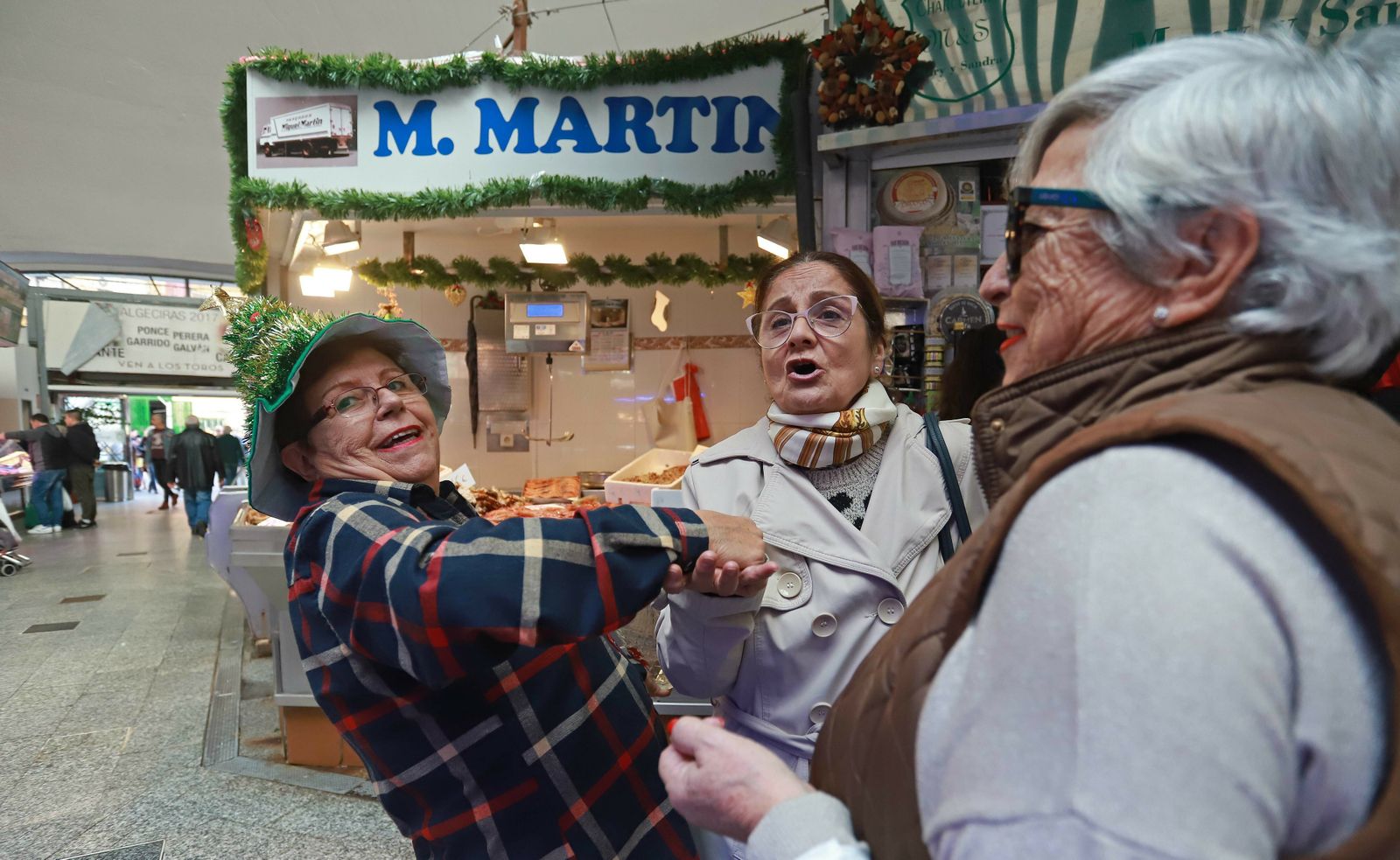 Una clienta de Charcutería Mary y Sandra ameniza la espera con un cante en la plaza de abastos de Algeciras.