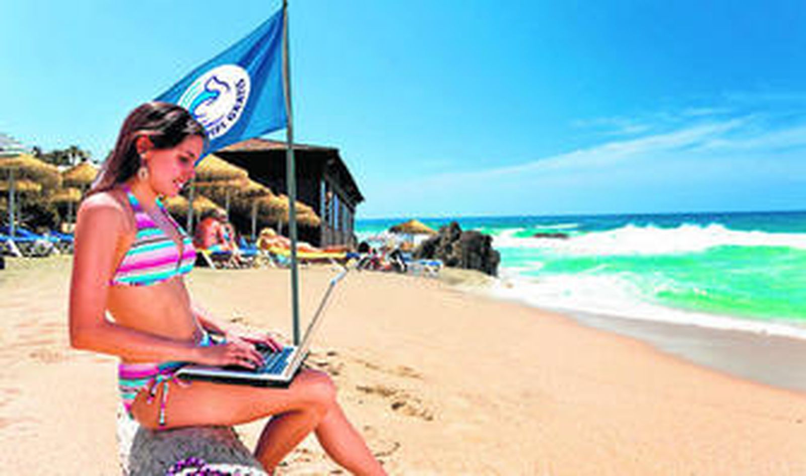 Una bañista consulta internet en la playa.