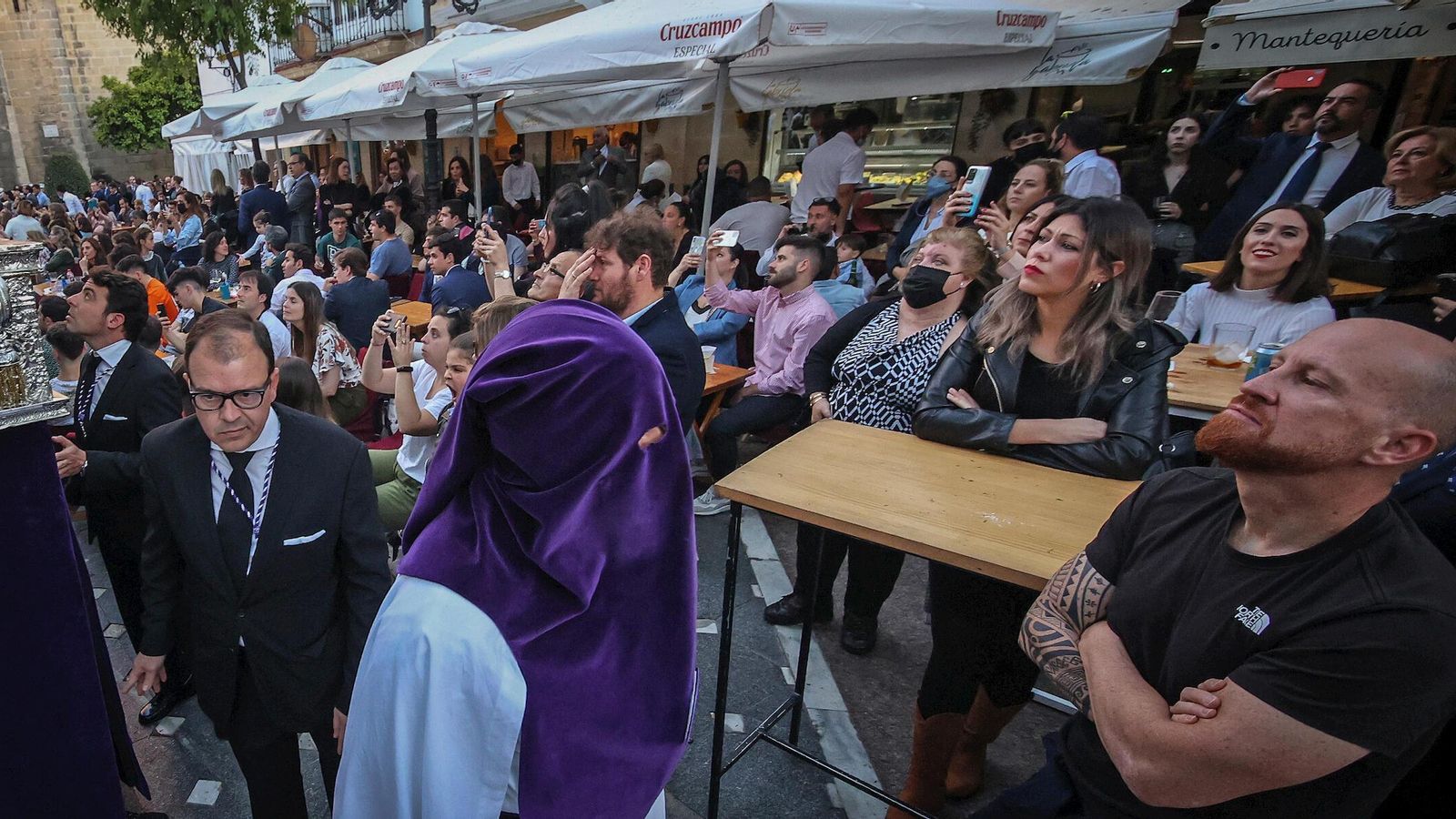 Una procesión pasa junto a terrazas del centro llenas.