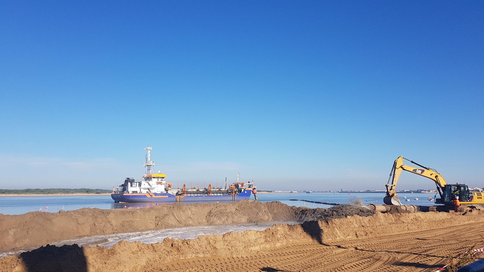 Una draga vierte mediante una tubería los sedimentos del río en la playa de Sanlúcar.
