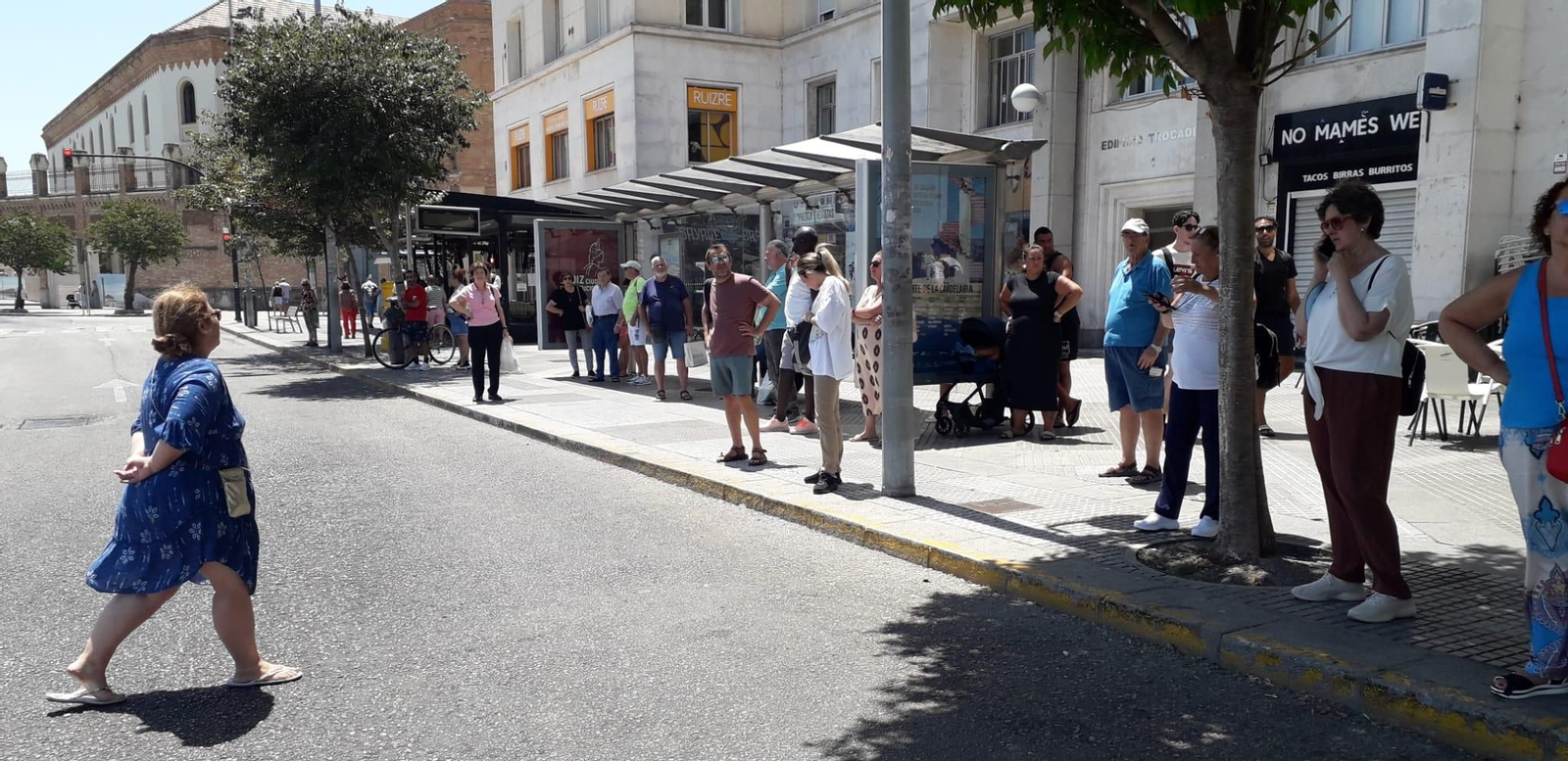 Ciudadanos esperando en una parada uno de los autobuses de los servicios mínimos.