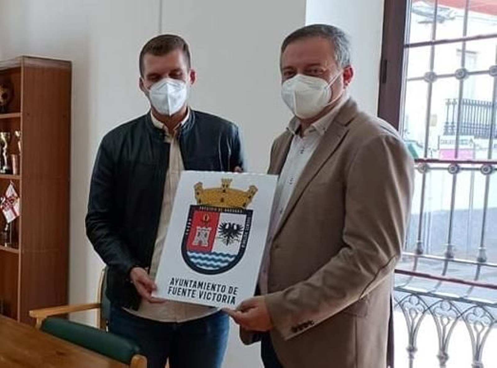 El alcalde de Fuente Victoria y el delegado de Administración Local muestran el escudo.