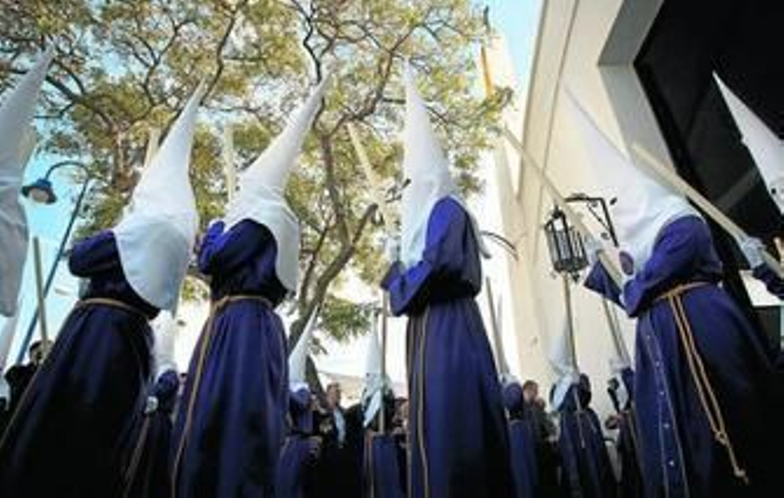 Nazarenos de la hermandad del Gran Poder abriendo con decisión la tarde del Miércoles Santo, cirios en alto, desde el barrio de la Bazán.