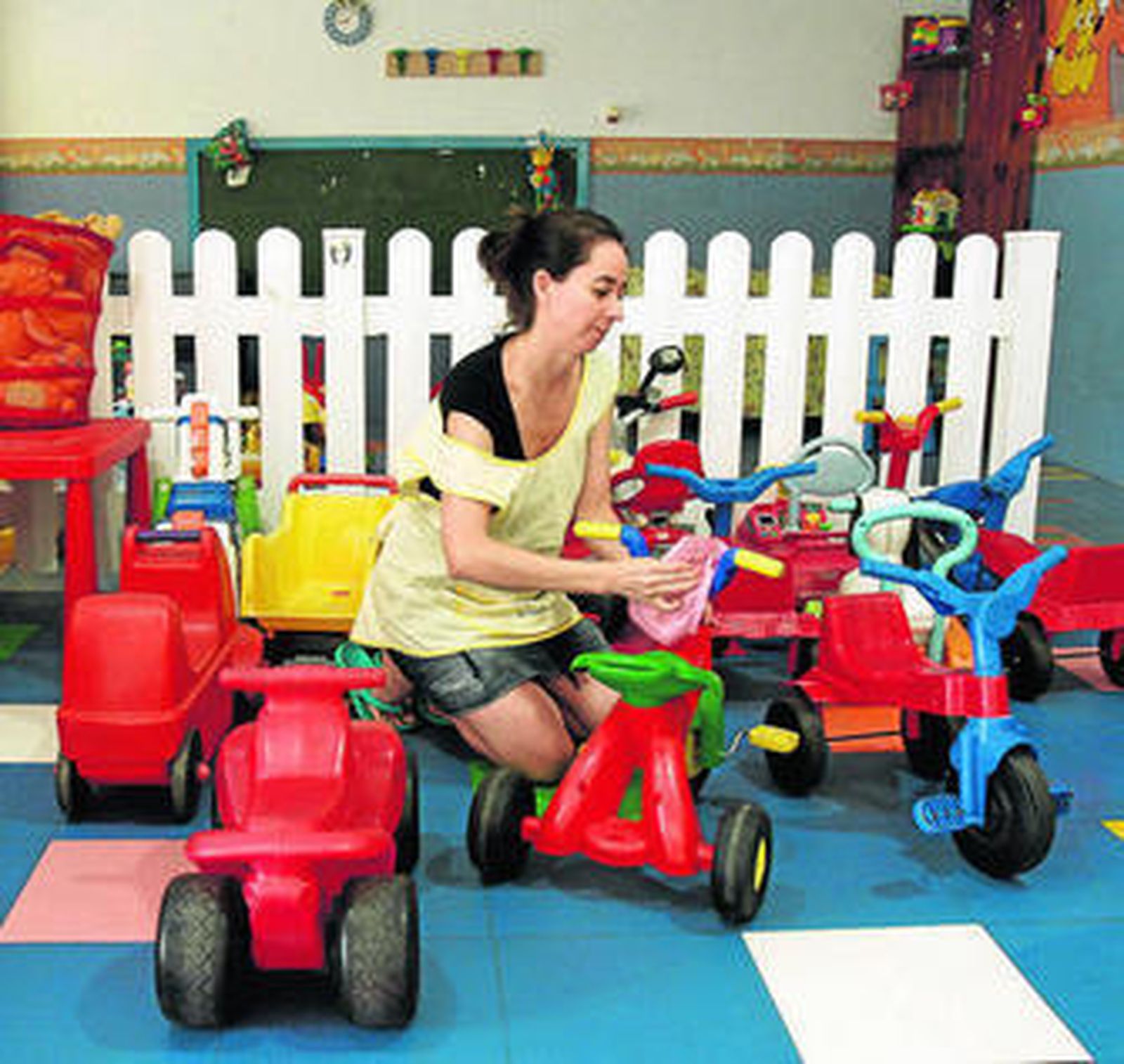 La trabajadora de una guardería limpia los juguetes que usarán los niños.