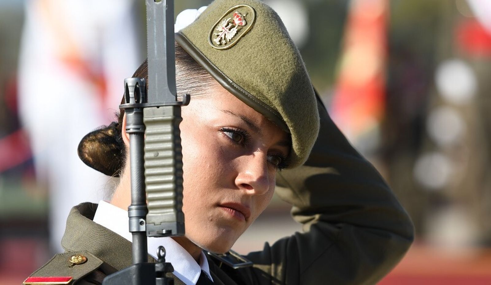 Una de las aspirantes se coloca la boina del uniforme tras el paso a uno bajo la bandera que refrenda el juramento.