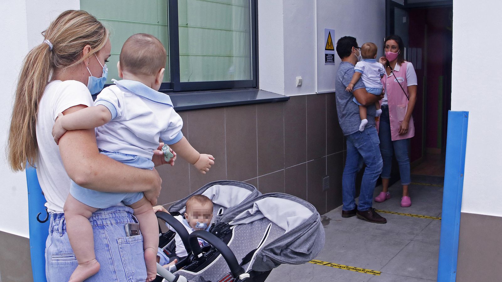 Los padres llevan a sus hijos a la guardería manteniendo la distancia de seguridad.