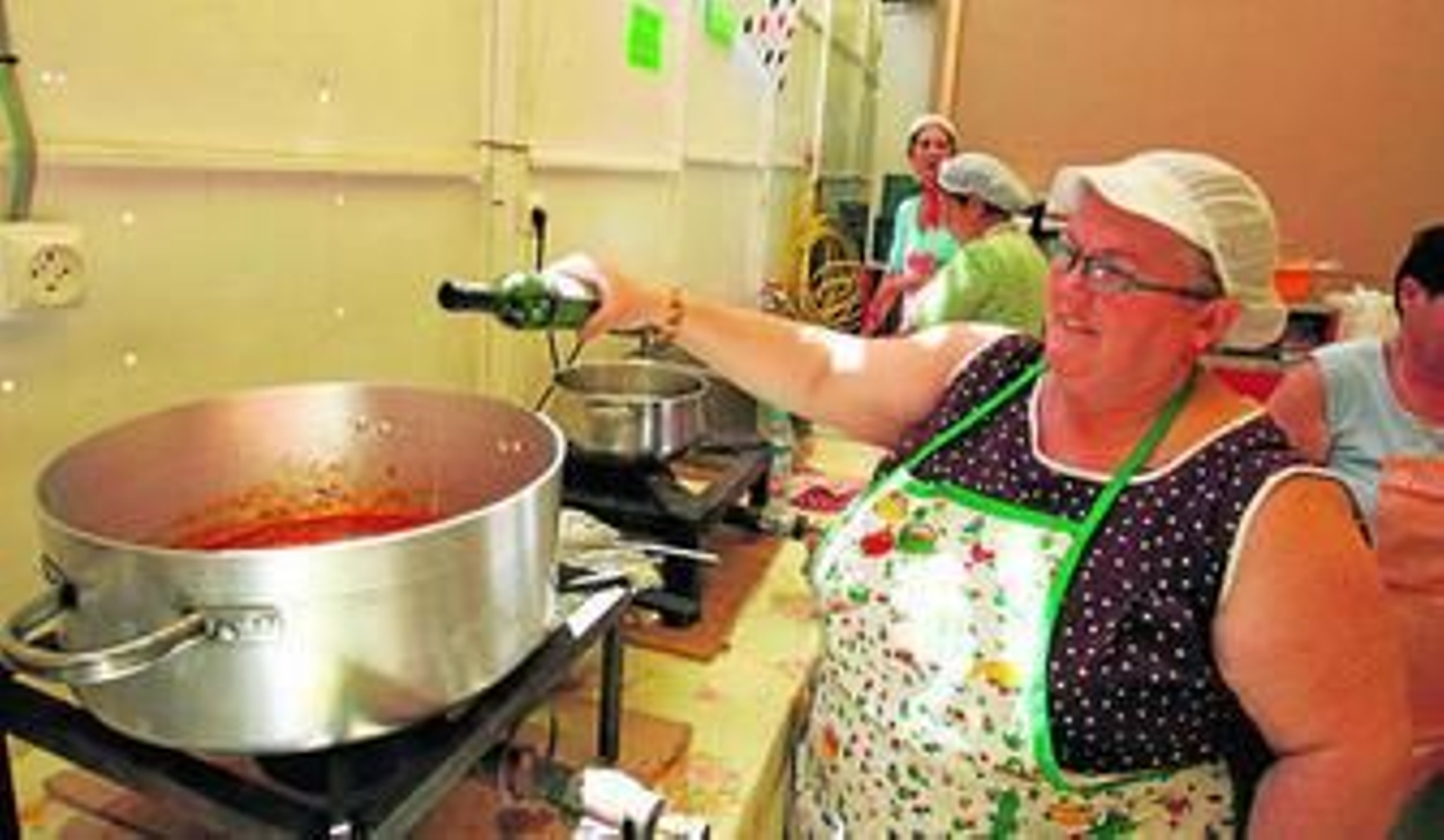 Una mujer echa vino al guiso en la cocina de una caseta de la Feria.