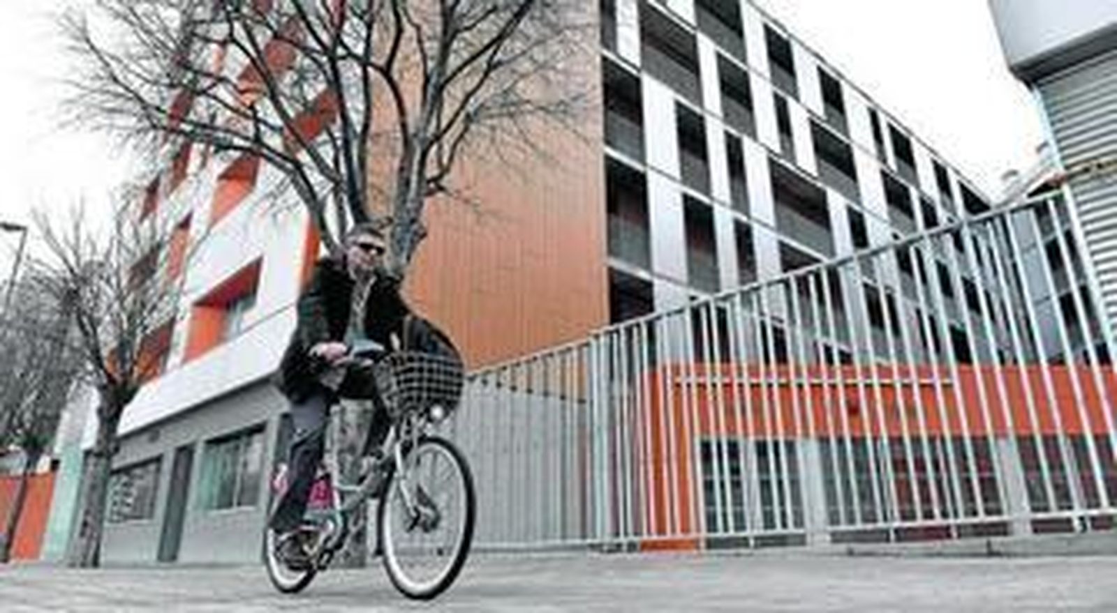 Un hombre pasea en bicicleta junto a un edificio del parque de vivienda pública en el barrio de Nervión.