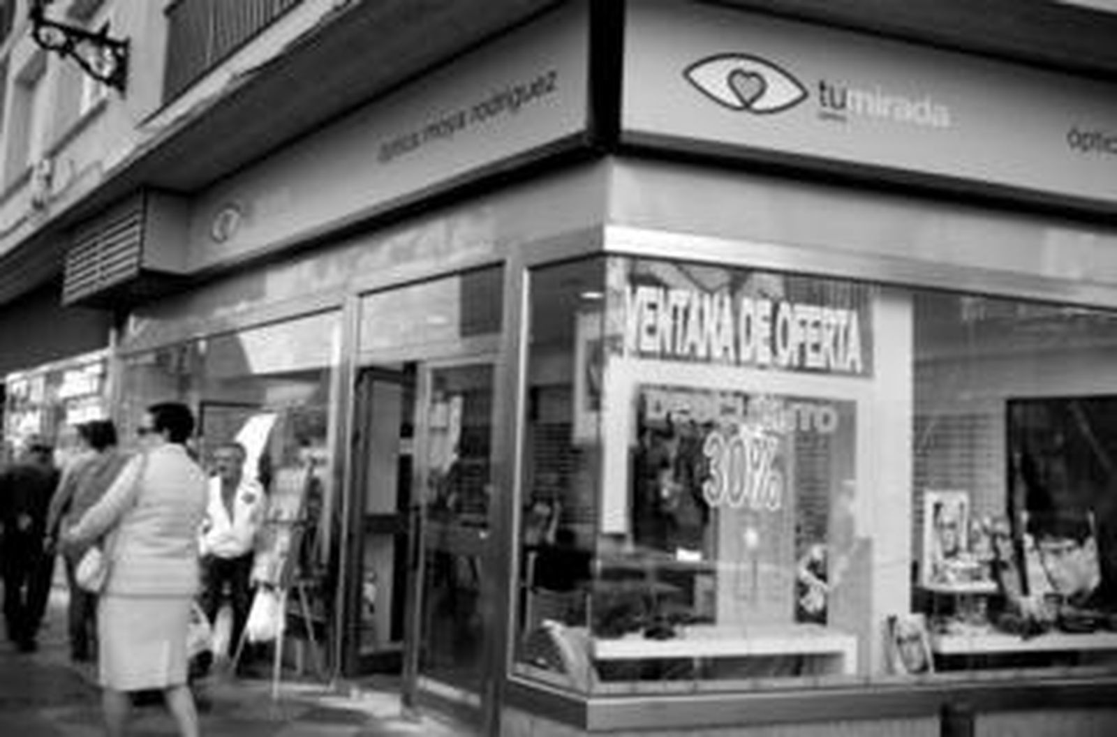 Imagen de la óptica, ayer, con el escaparate roto justo debajo del rótulo de la promoción.