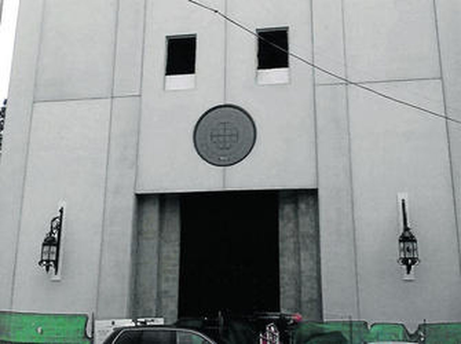 Vista parcial de la fachada de la nueva capilla, en la que se han colocado la puerta, vidriera y faroles.