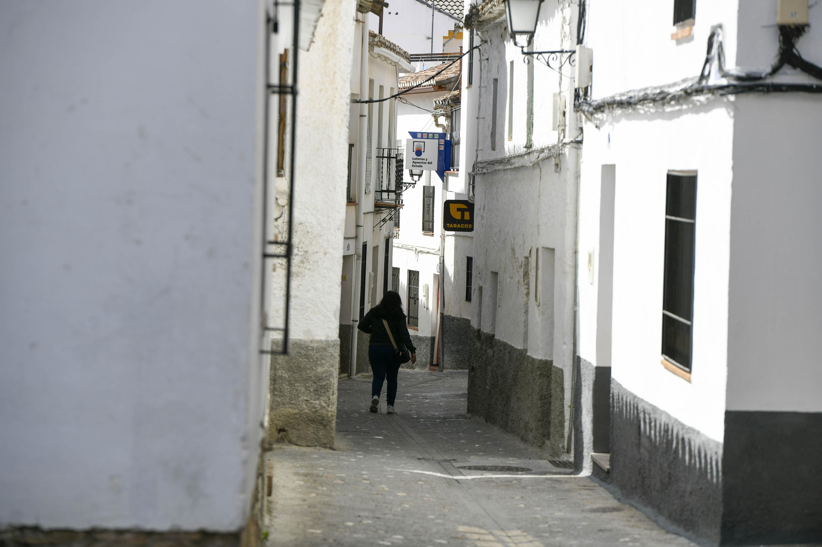 Una mujer camina por una calle de Huétor Santillán, una población con prácticamente la misma cantidad de habitantes que infectados por Covid-19 hay en Granada
