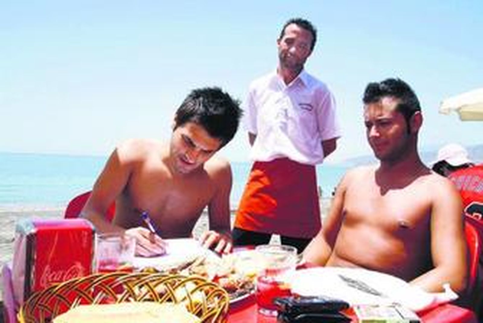 Dos jóvenes firman el libro de apoyo a la permanencia de los chiringuitos en la playa.