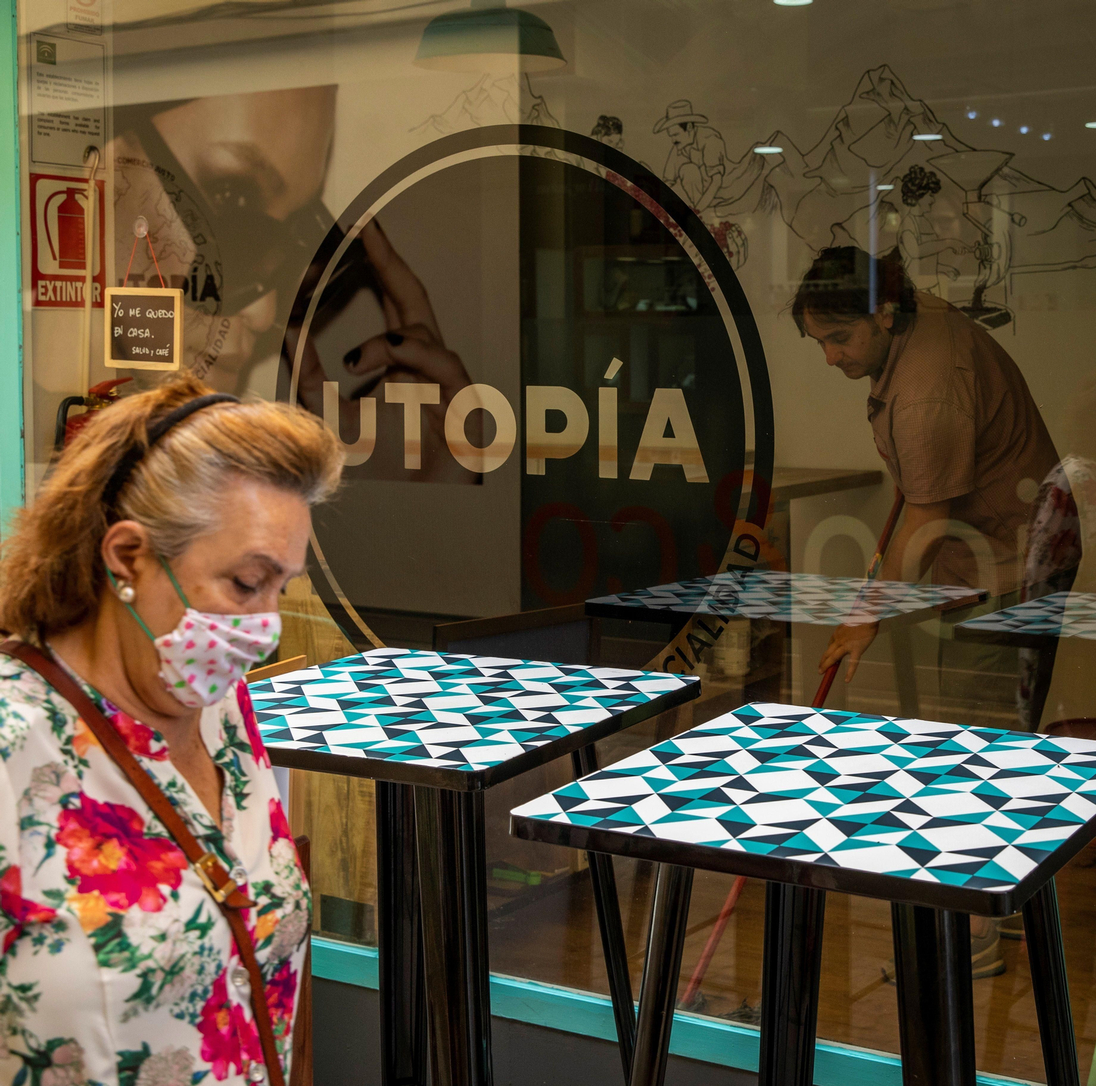 Un comerciante limpia el interior de su establecimiento en el centro de Sevilla.