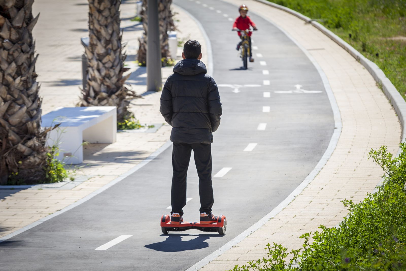 Un joven circulando correctamente con un vehículo de movilidad personal por el carril bici.