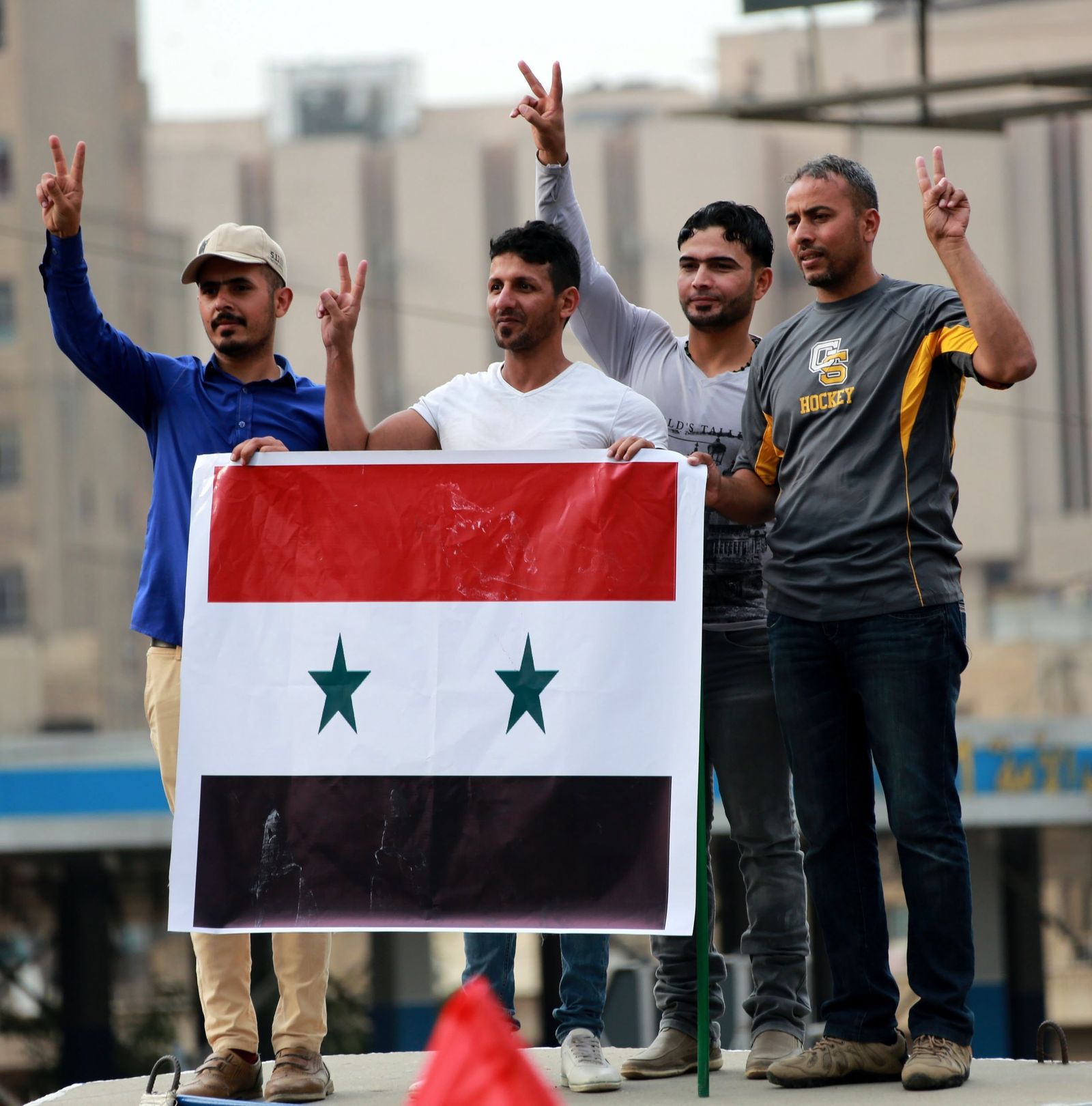 Partidarios del régimen sirio portan una bandera del país en Bagdad (Iraq).