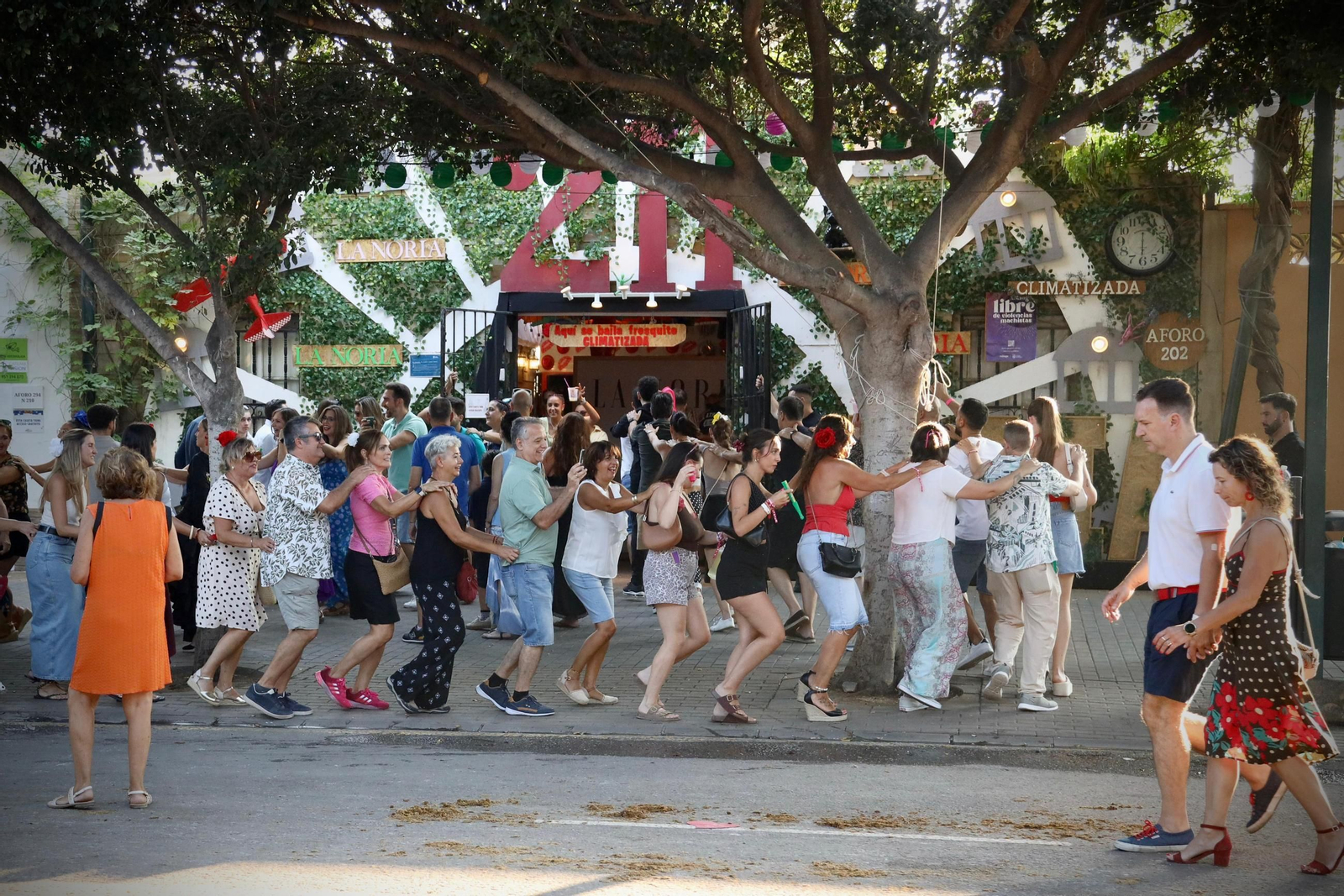 Un grupo de personas bailan la conga en el último día de Feria en el Real.