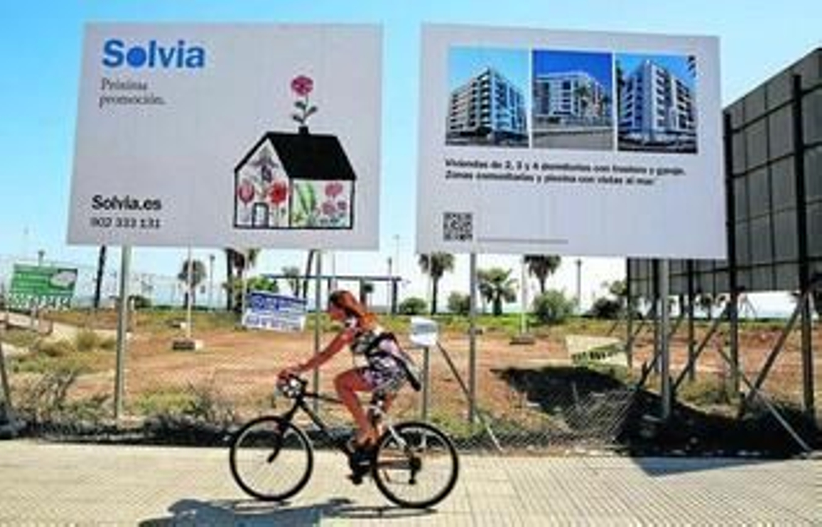 Una ciclista pasa junto al terreno en el que se anuncia la futura promoción inmobiliaria en la zona oeste de la capital.