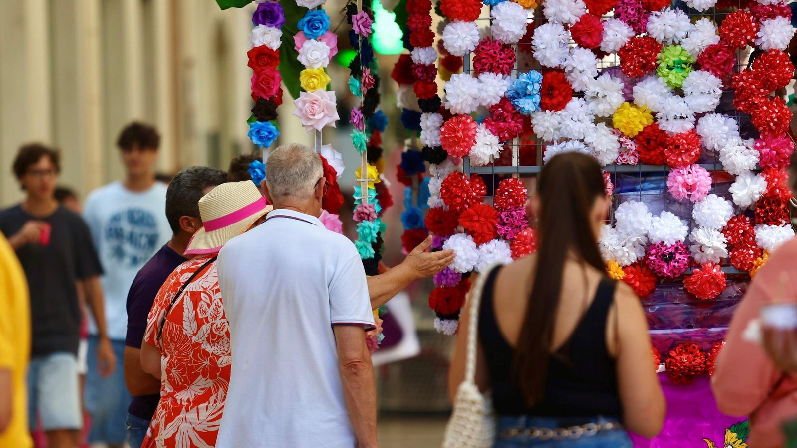 Varias personas revisan los productos de un puesto ambulante.