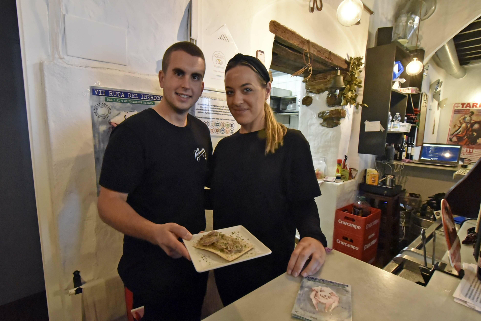 Dos camareros muestran una de las tapas participantes en la Ruta del Ibérico de Tarifa.