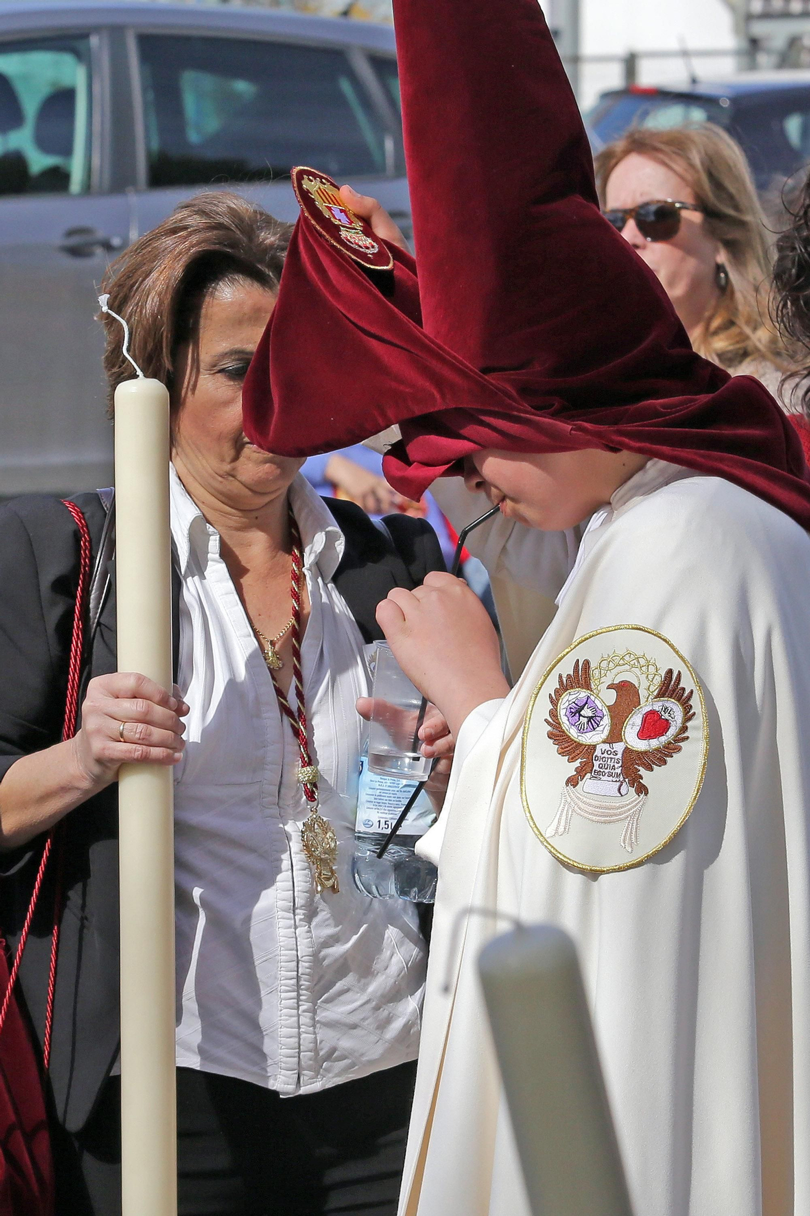 Un nazareno toma un refresco en una calurosa tarde de Semana Santa.