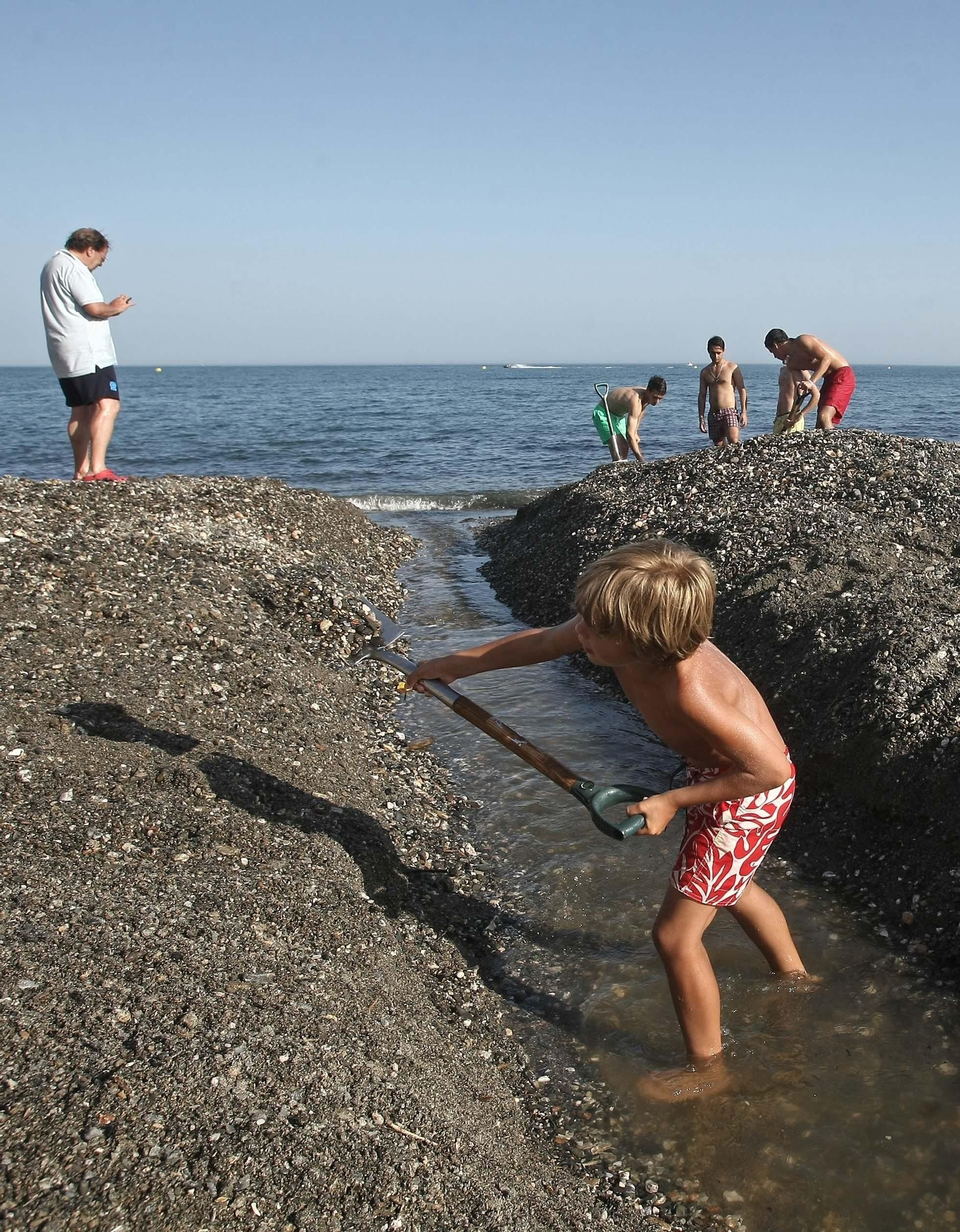 Un niño colabora en la apertura de la desembocadura, el pasado julio.