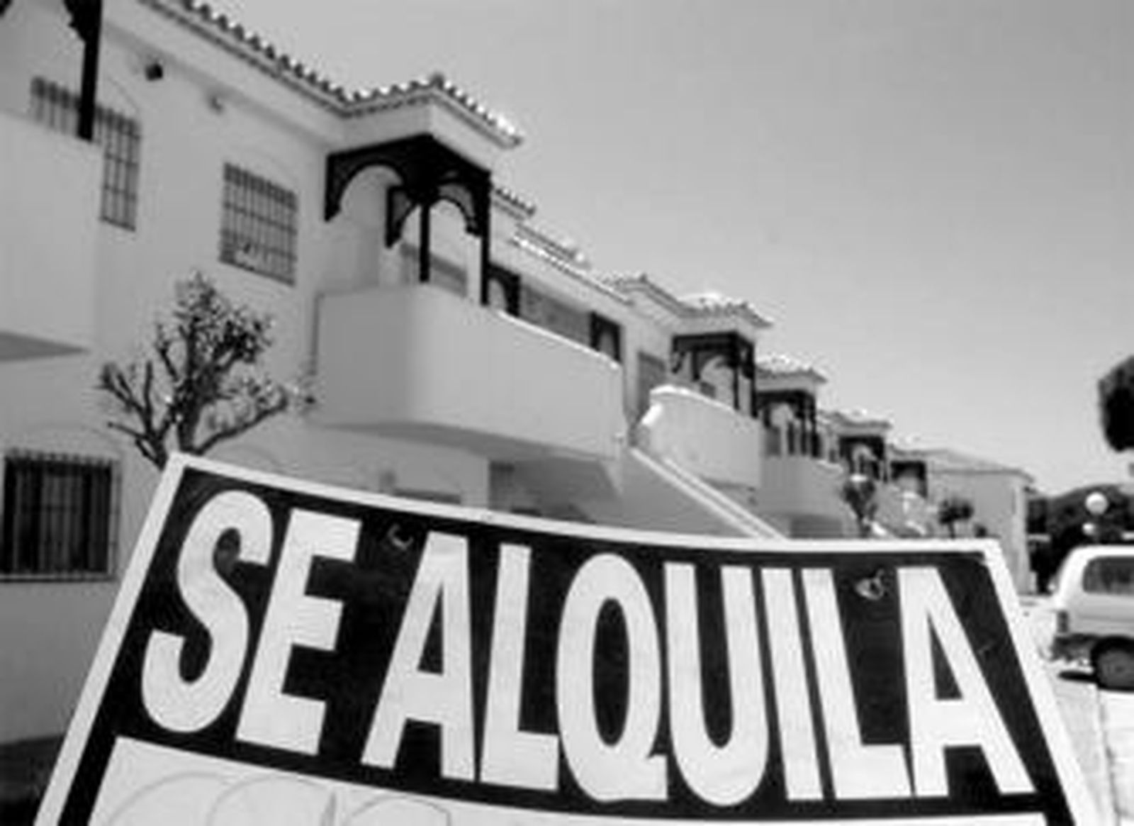 Un gran cartel de 'Se alquila' junto a varias viviendas turísticas en la costa.