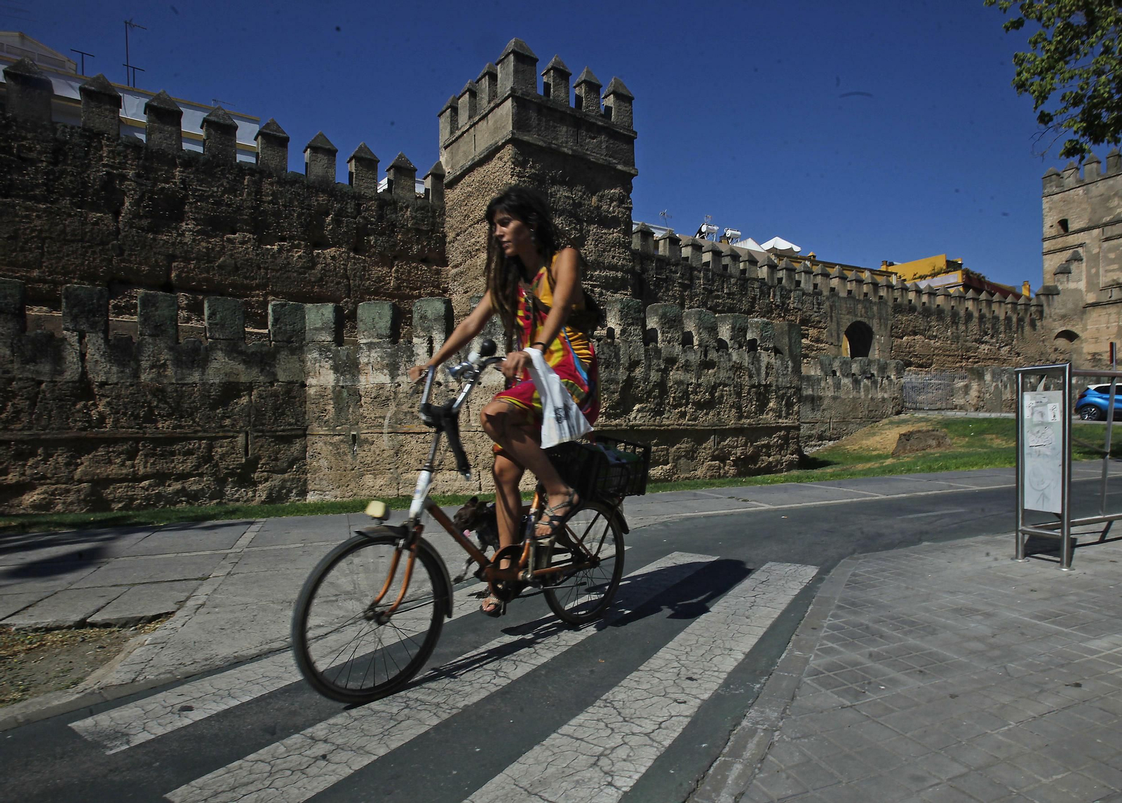Una joven circula por el carril bici junto a la Muralla de la Macarena.