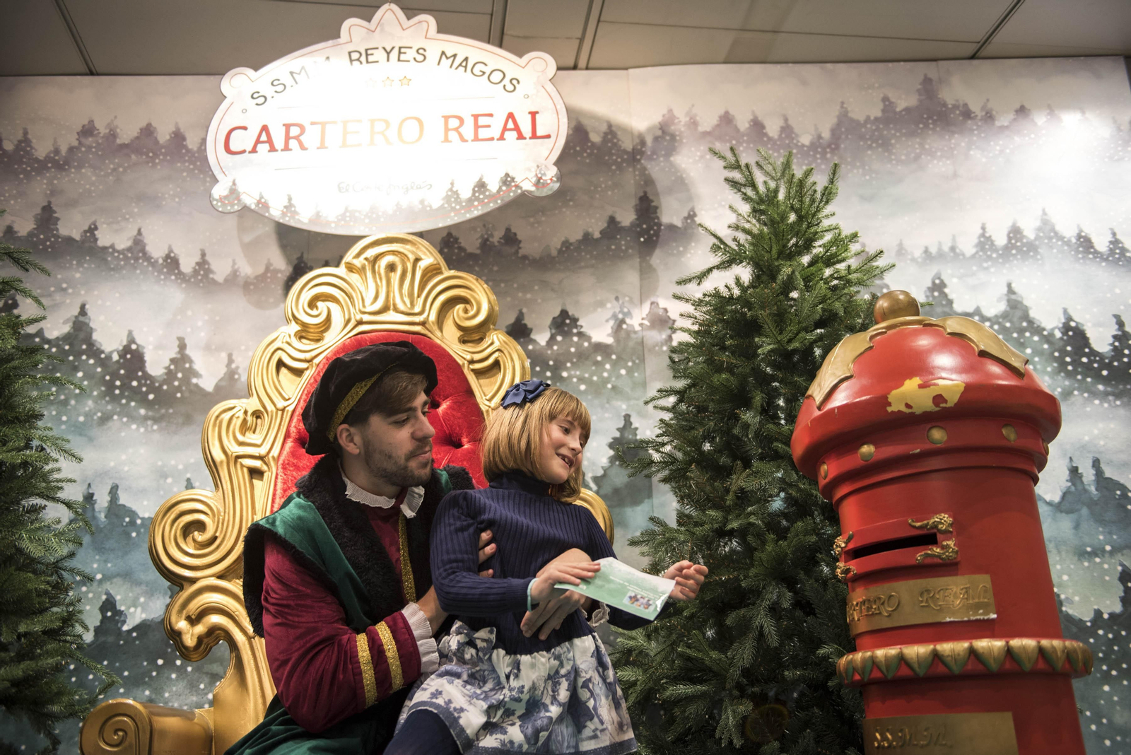 El cartero real ayuda a una pequeña a hacer llegar su petición a los Reyes Magos de Oriente.