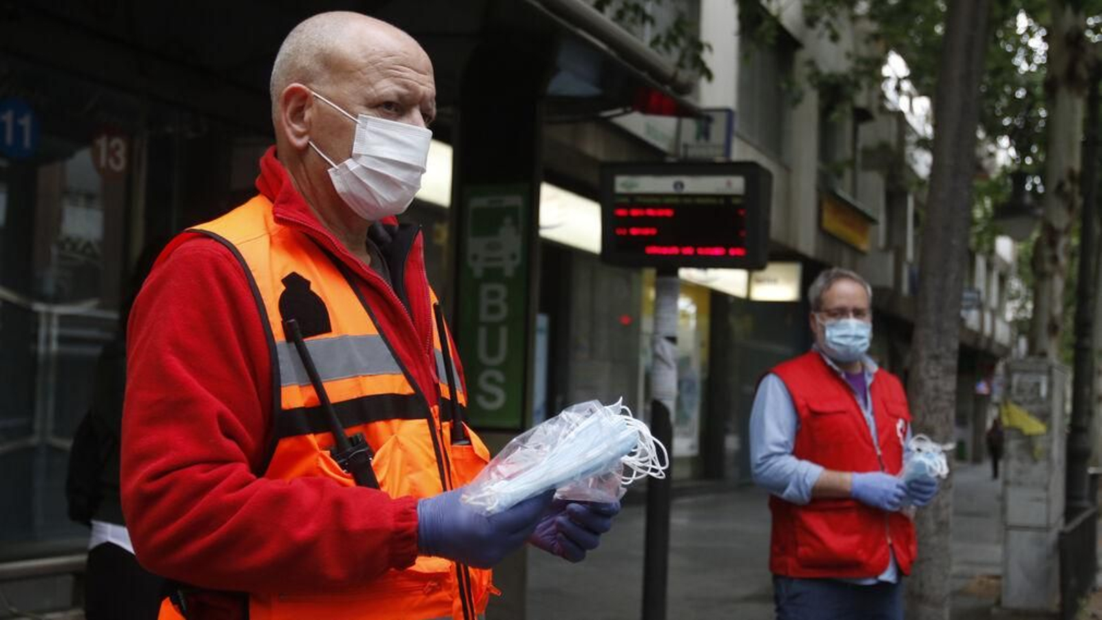 Dos voluntarios esperan en una parada del autobús.