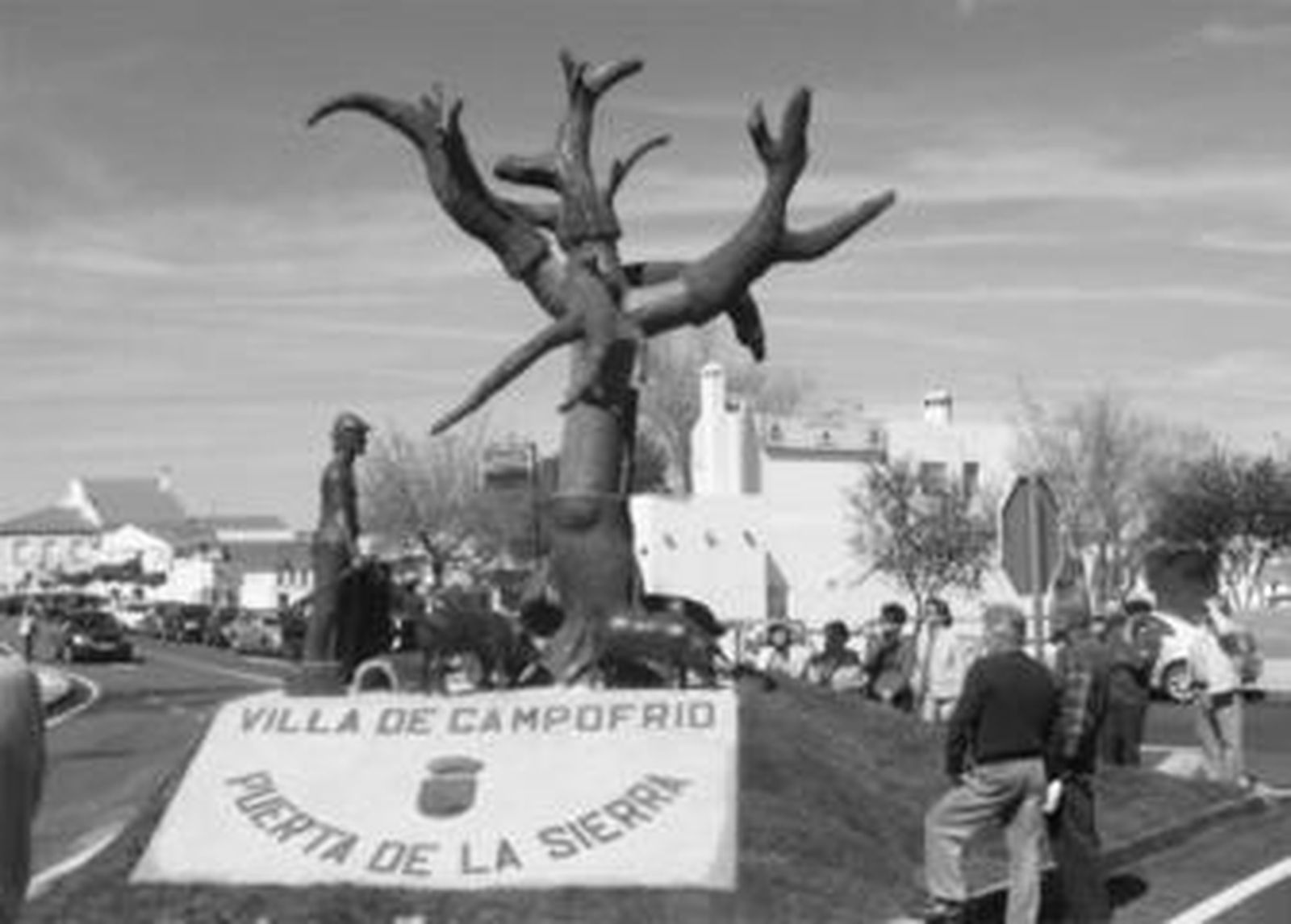 Vecinos de Campofrío contemplan la escultura de bronce situada a la entrada del municipio.