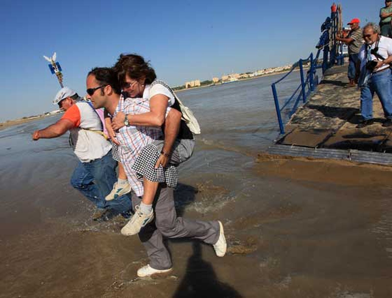 Un romero carga sobre sus espaldas a una rociera tratando de impedir que se moje durante el embarque.  

Foto: Juan Carlos Toro