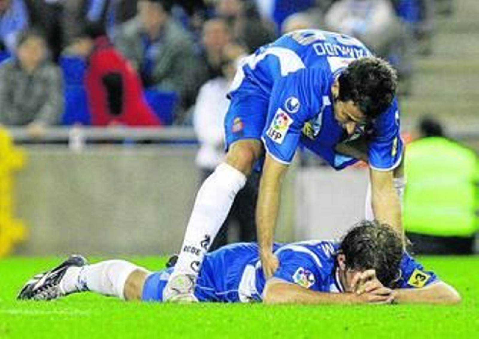 Raúl Tamudo levanta a su compañero Iván Alonso, en el suelo.