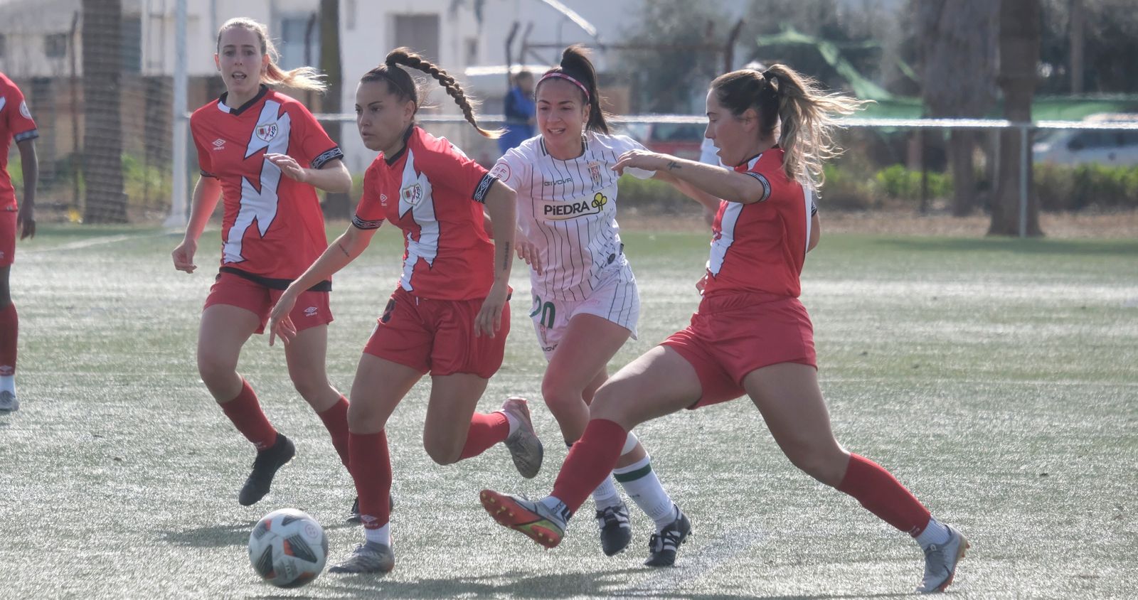 Elisa, jugadora del Córdoba Femenino, intenta superar a dos futbolistas del Rayo.
