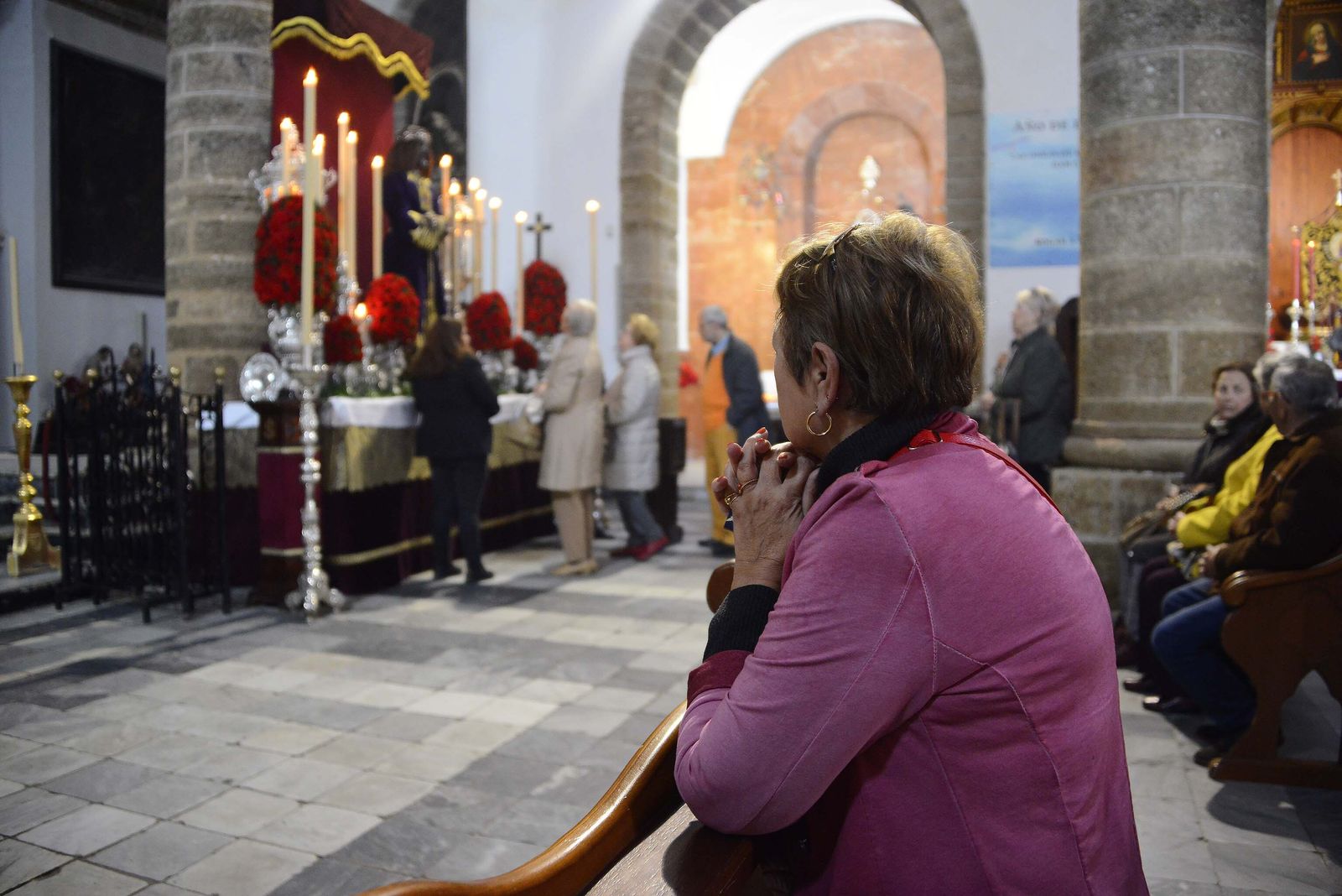 Una mujer reza en Santa Cruz con la imagen de Jesús de Medinaceli al fondo.