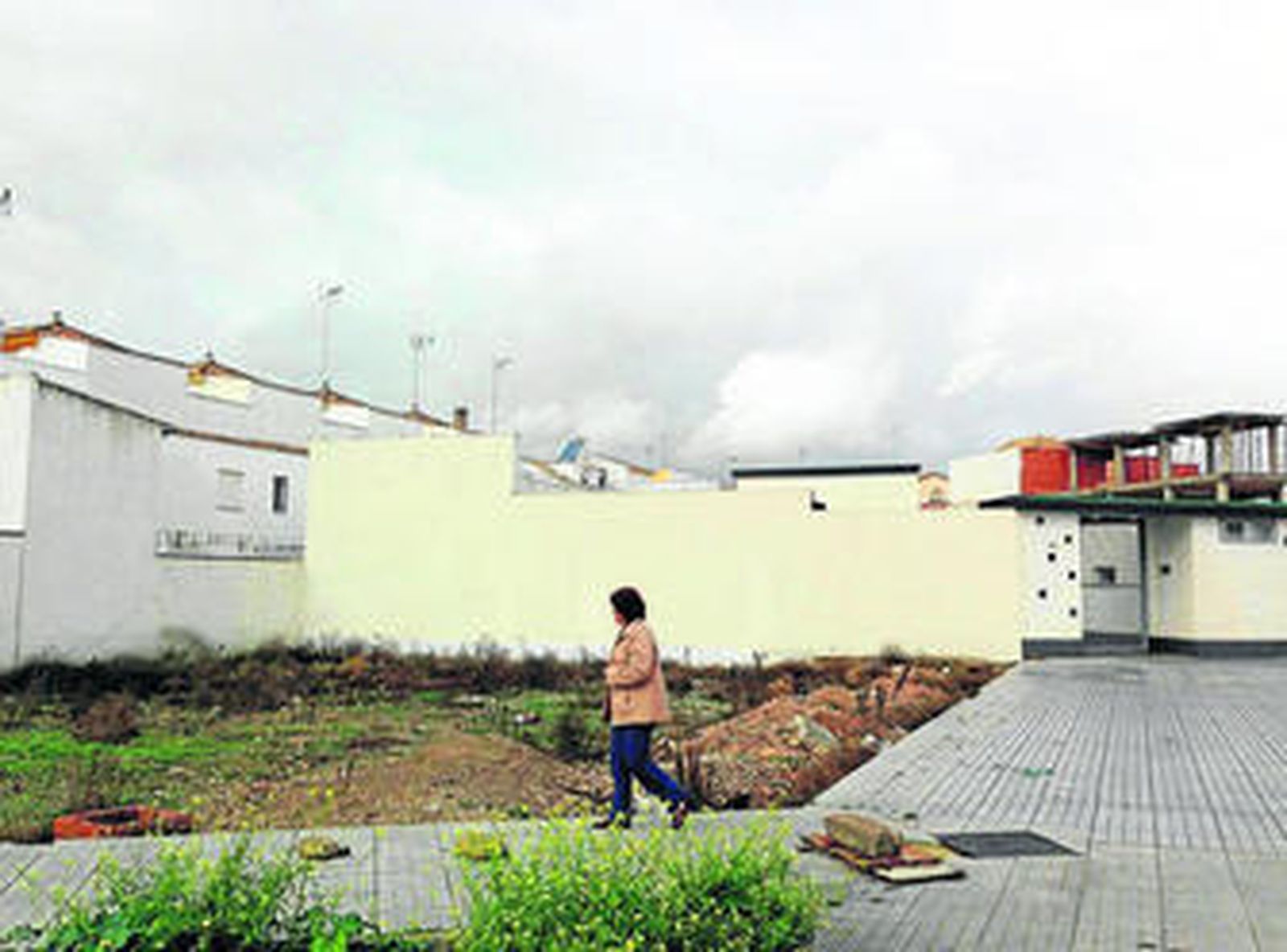Una mujer pasa junto a la parcela que albergará el nuevo inmueble.