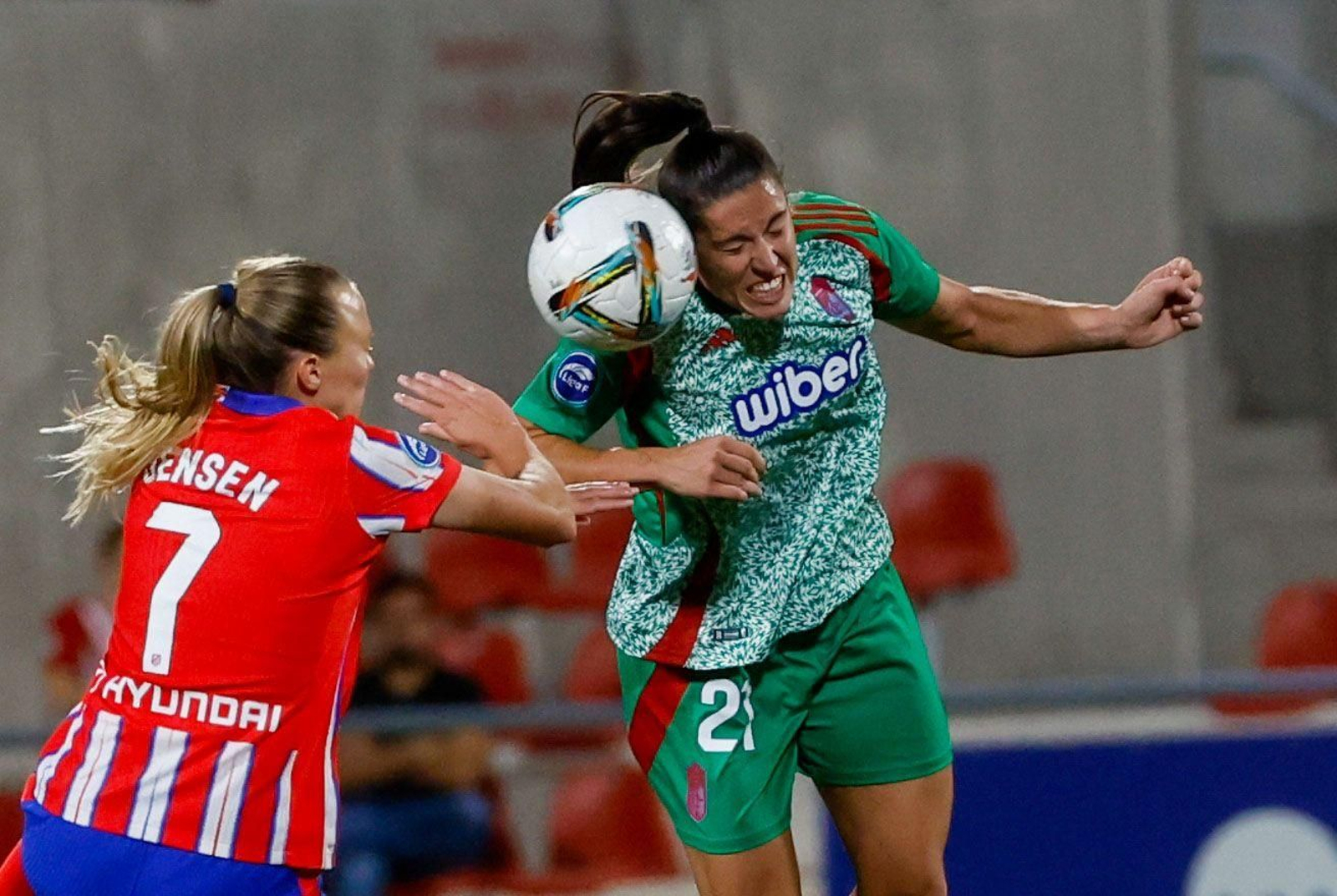 La jugadora del Granada CF femenino Postigo puga por un balón aéreo ante Jensen.