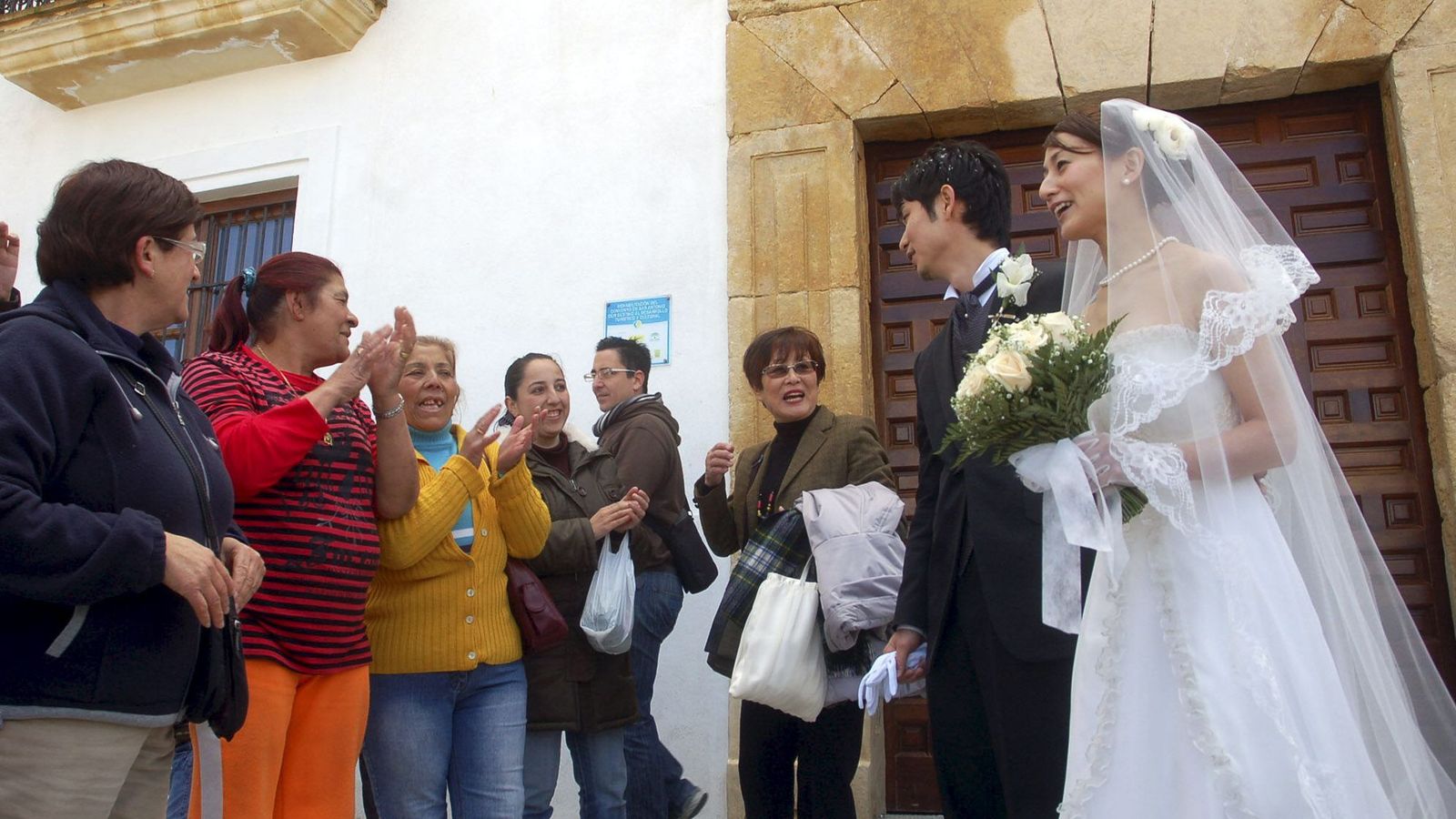 Vecinas del pueblo aplaudiendo a los novios japoneses durante el día del enlace.
