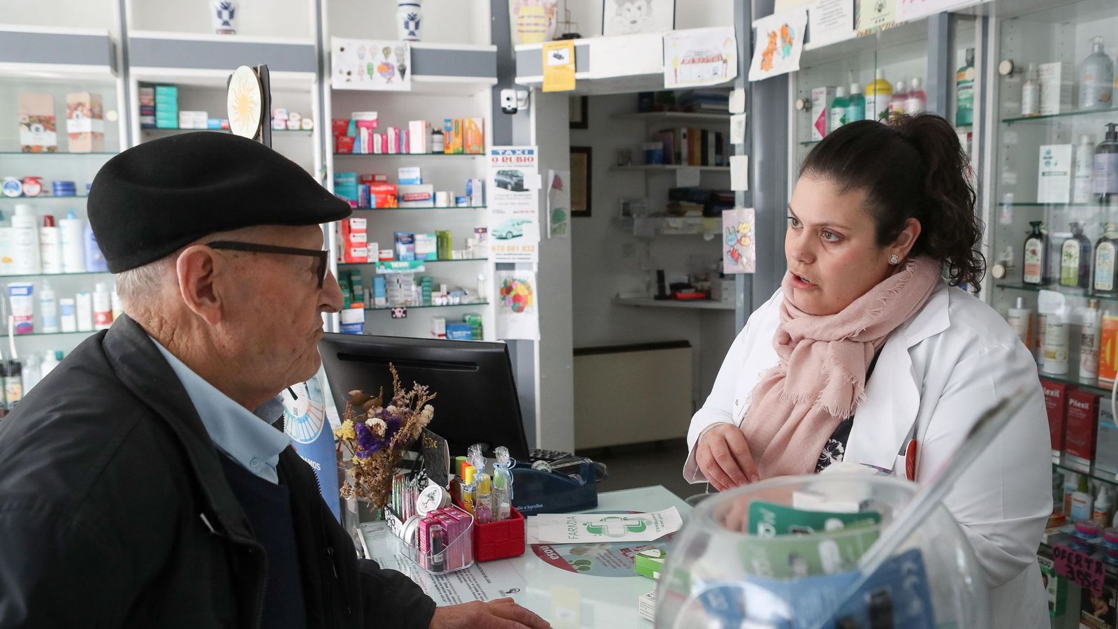 Un anciano pide un medicamento en una farmacia.