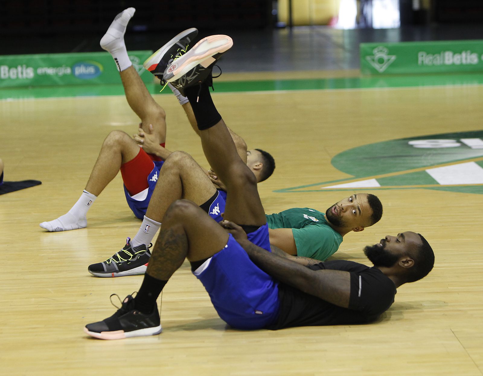 Conger y K.C. Rivers dialogan mientras hacen ejercicios de estiramientos.